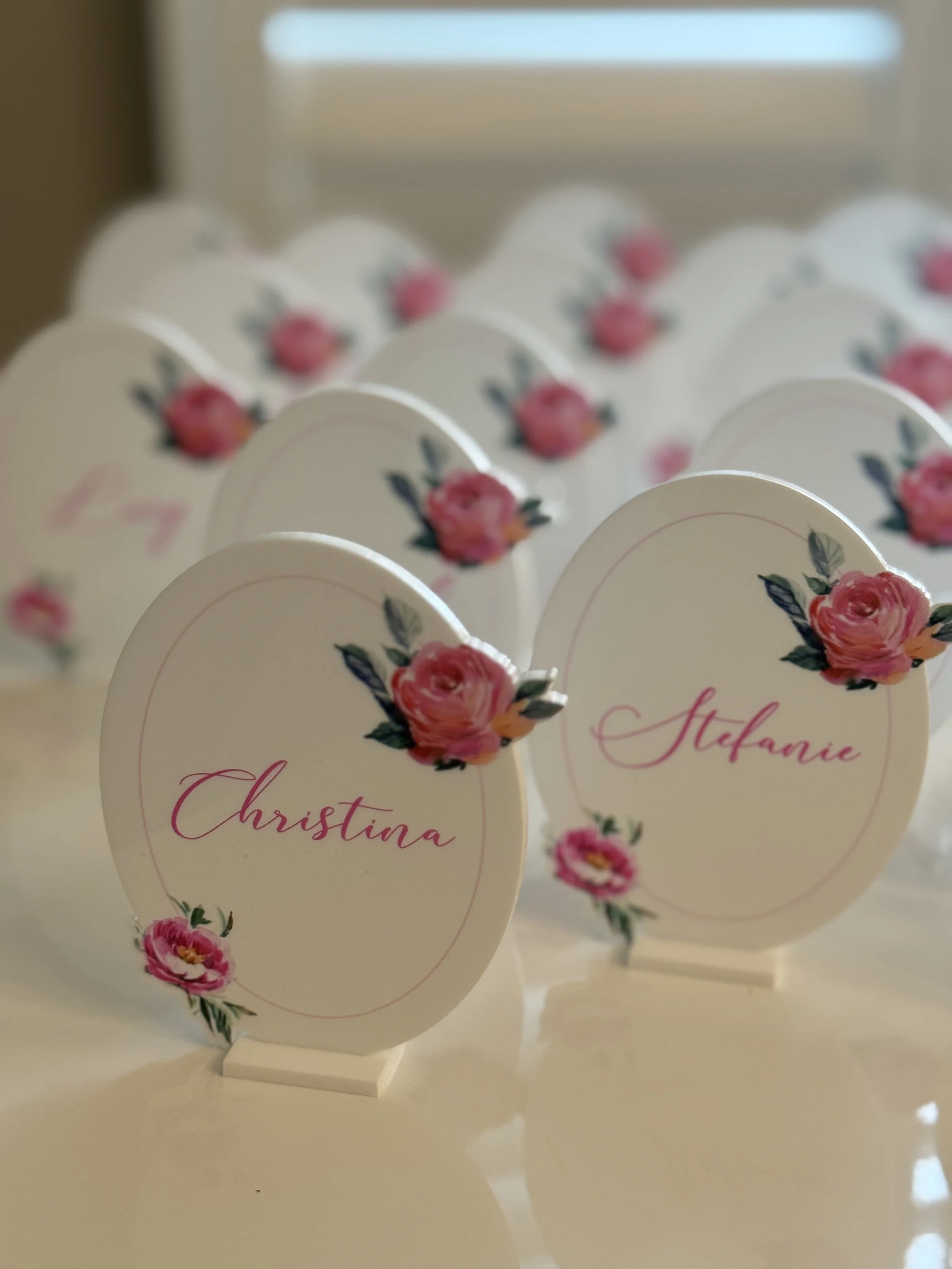 Table markers with pink floral designs and names 'Christina' and 'Stefanie' at a celebration event.