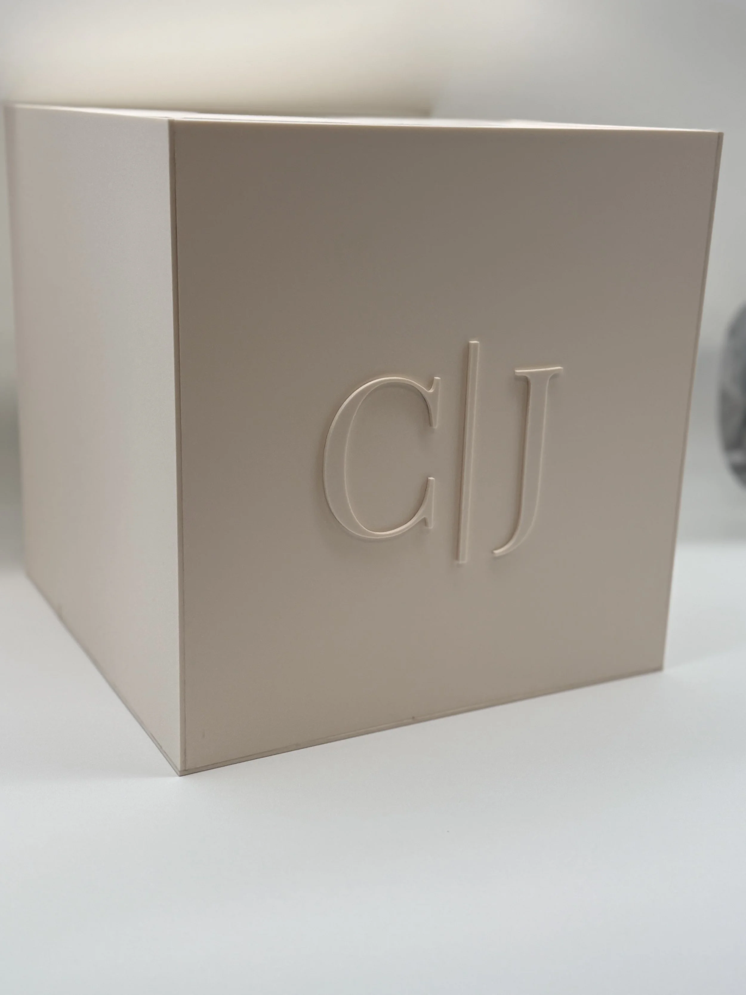 Beige box with the initials 'CJ' embossed on the front.
