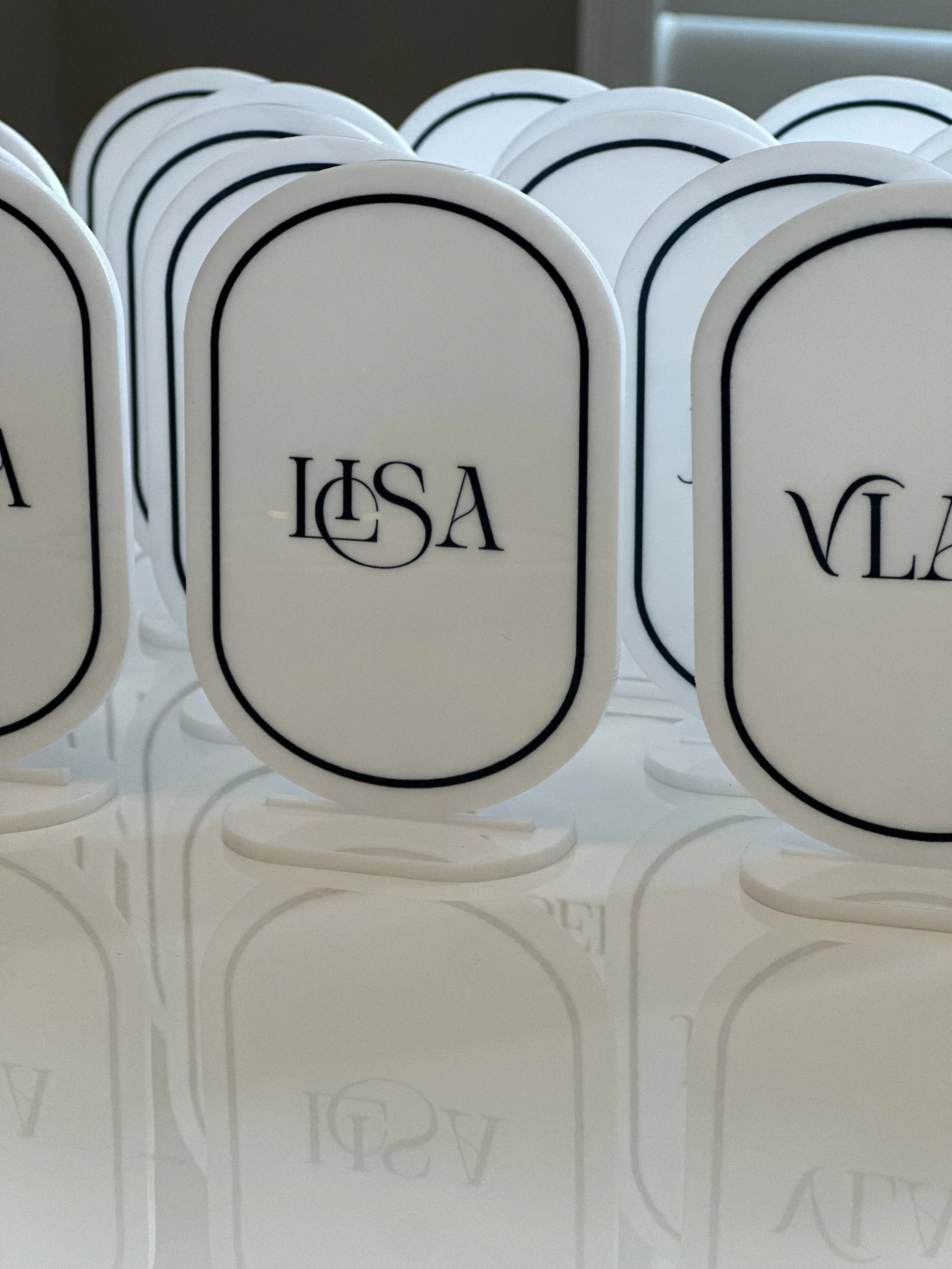 White oval signs with a black border and the letters "LSA" in black, arranged on a white surface.