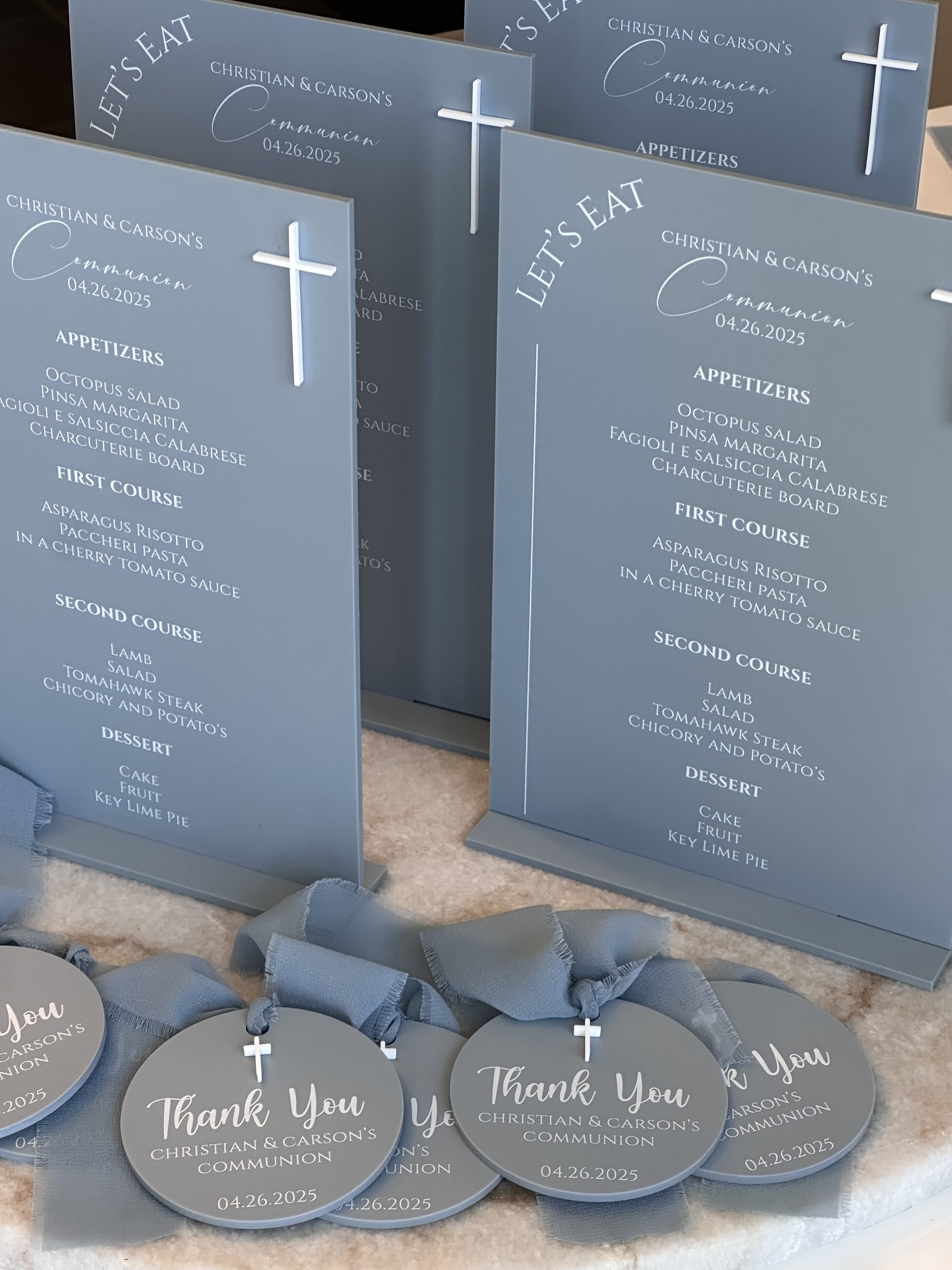 Set of blue communion programs and thank you tags with white crosses and ribbon accents, commemorating Christian & Carson's communion on April 26, 2025.