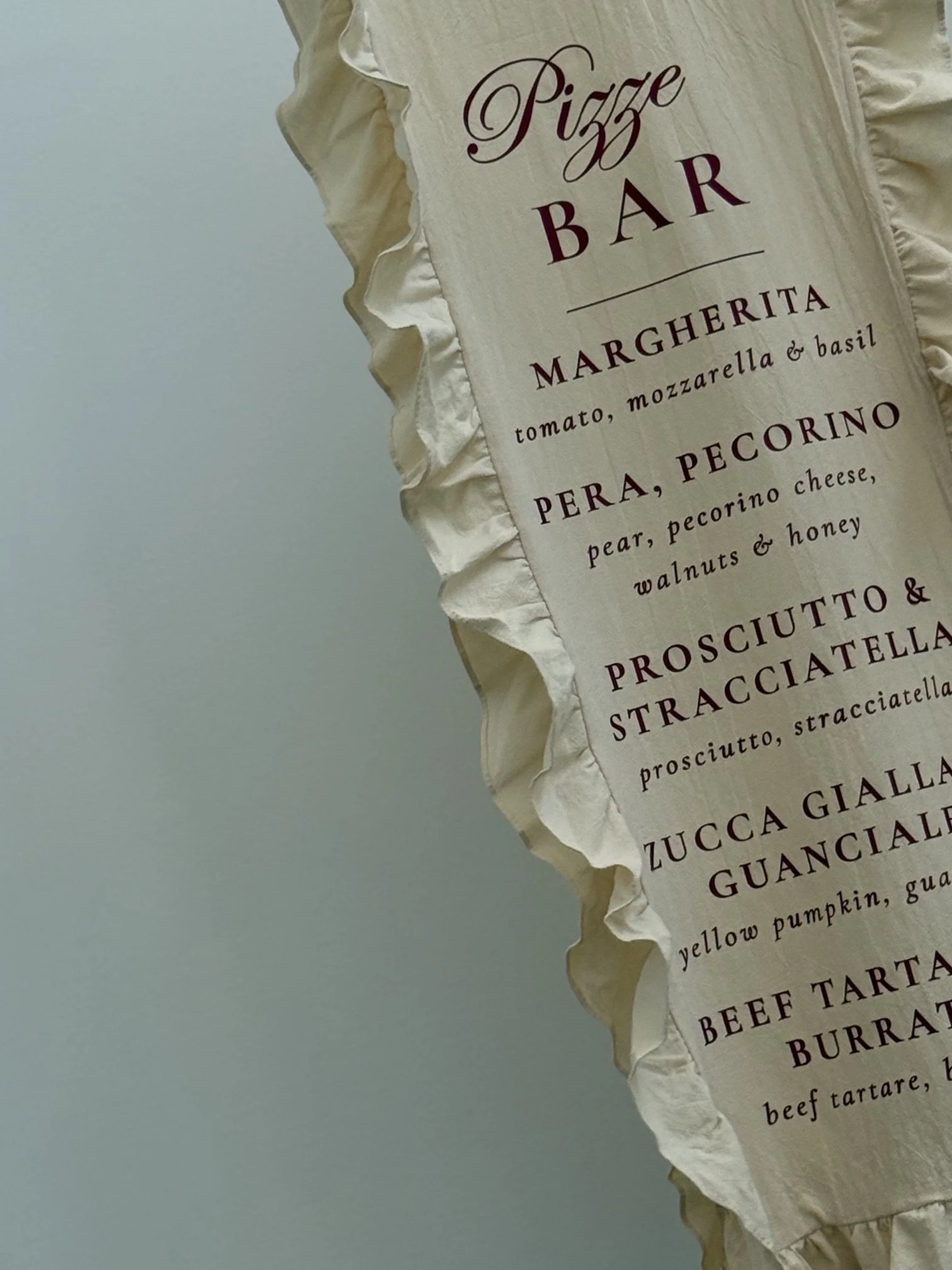 Close-up of a menu or sign with Italian dishes, including pizza, margherita, pera pecorino, and prosciutto
