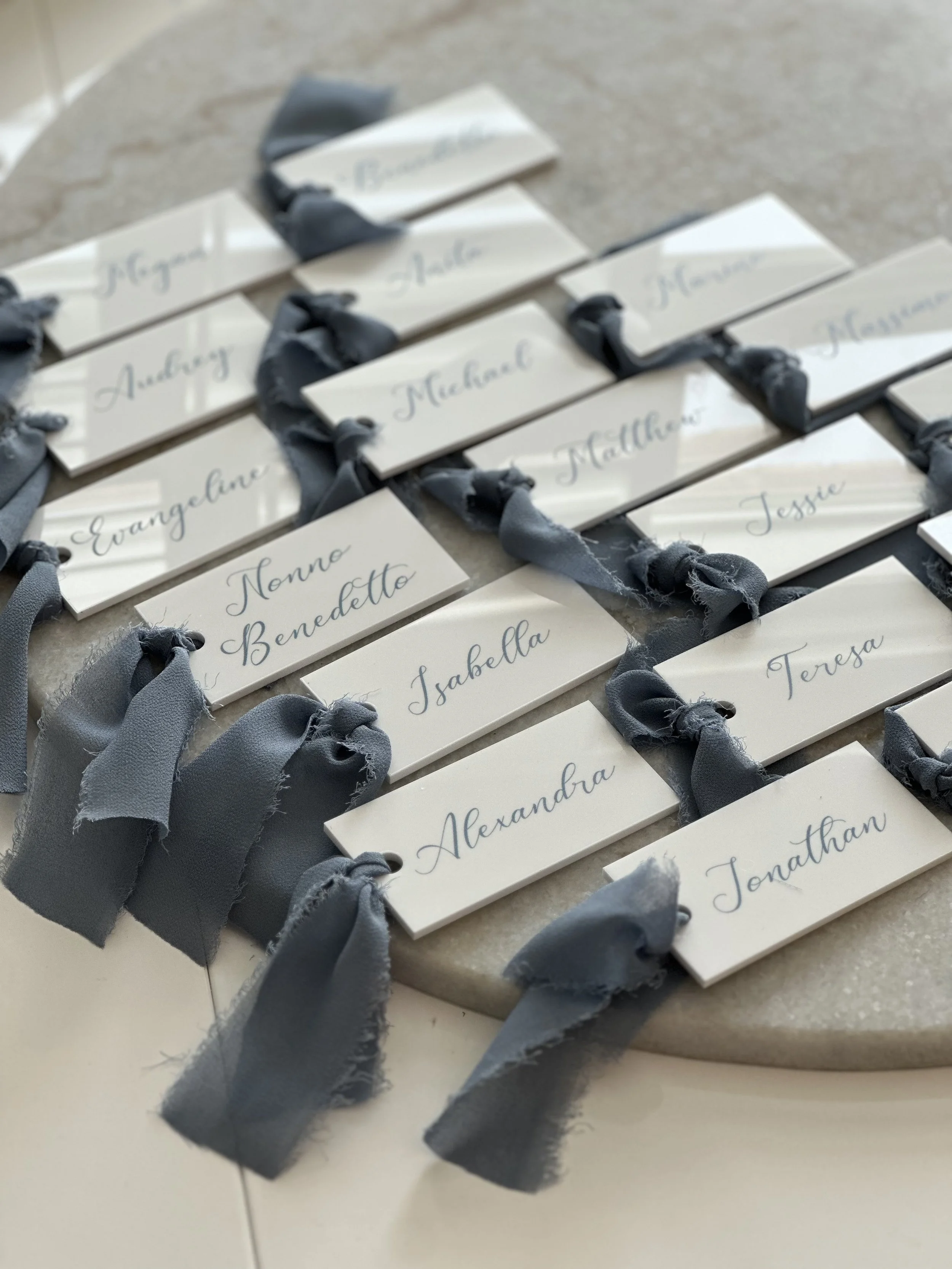 Wedding place cards with blue ribbons on a round table.
