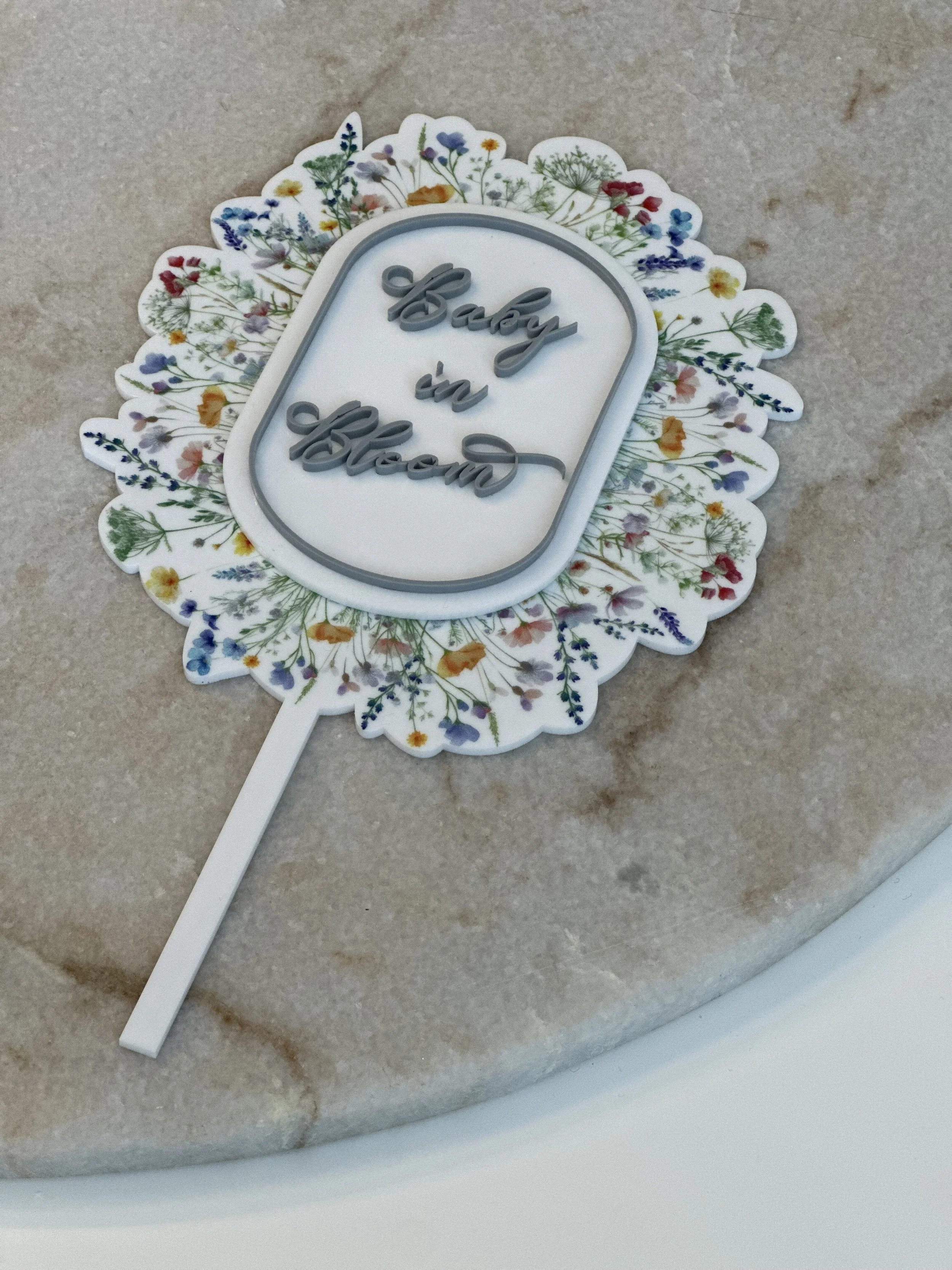 Decorative cake topper with the message 'Baby you go ahead' on a floral-patterned background.
