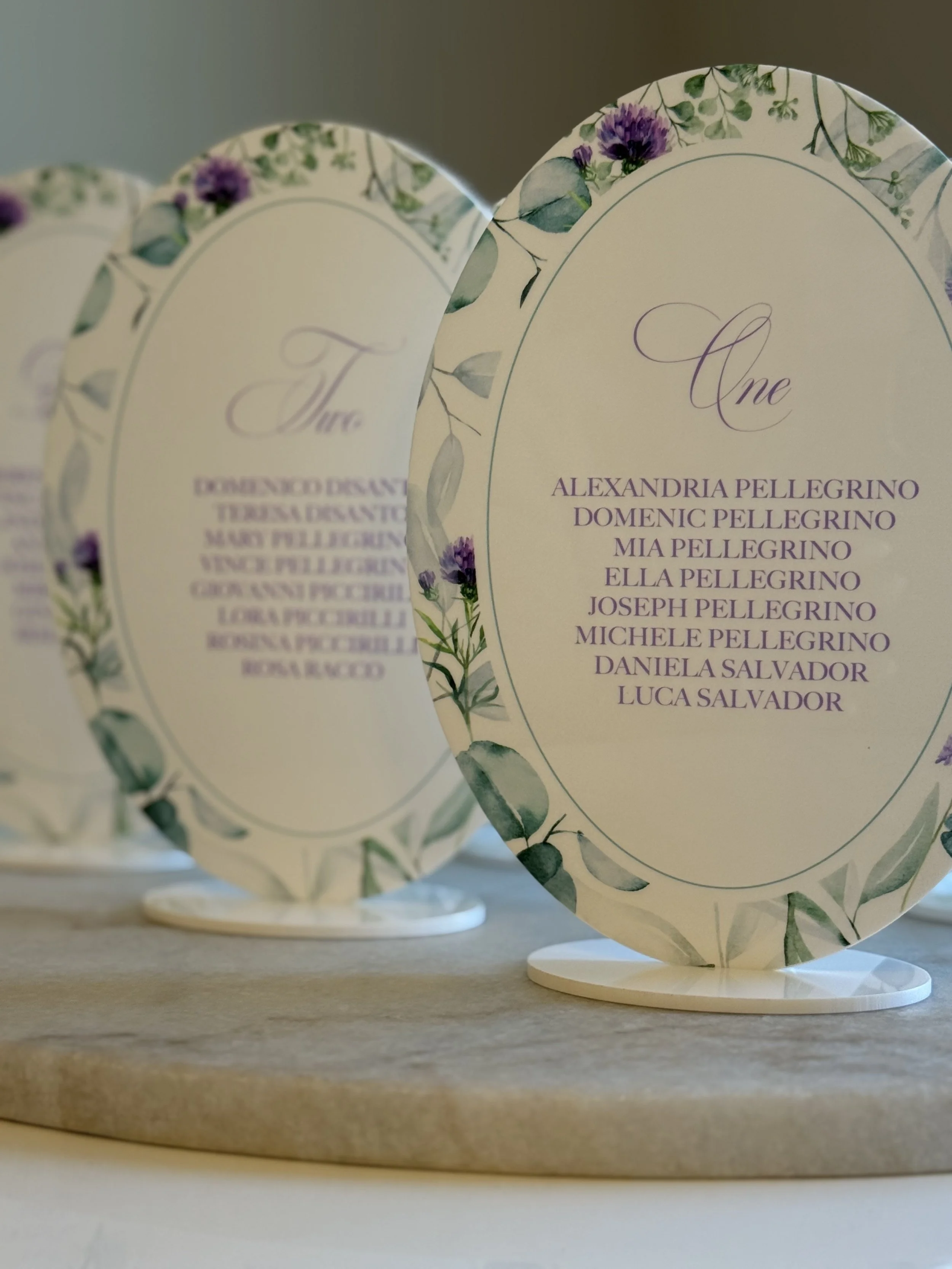 Wedding seating chart with floral border, list of names for one table, and elegant purple script.