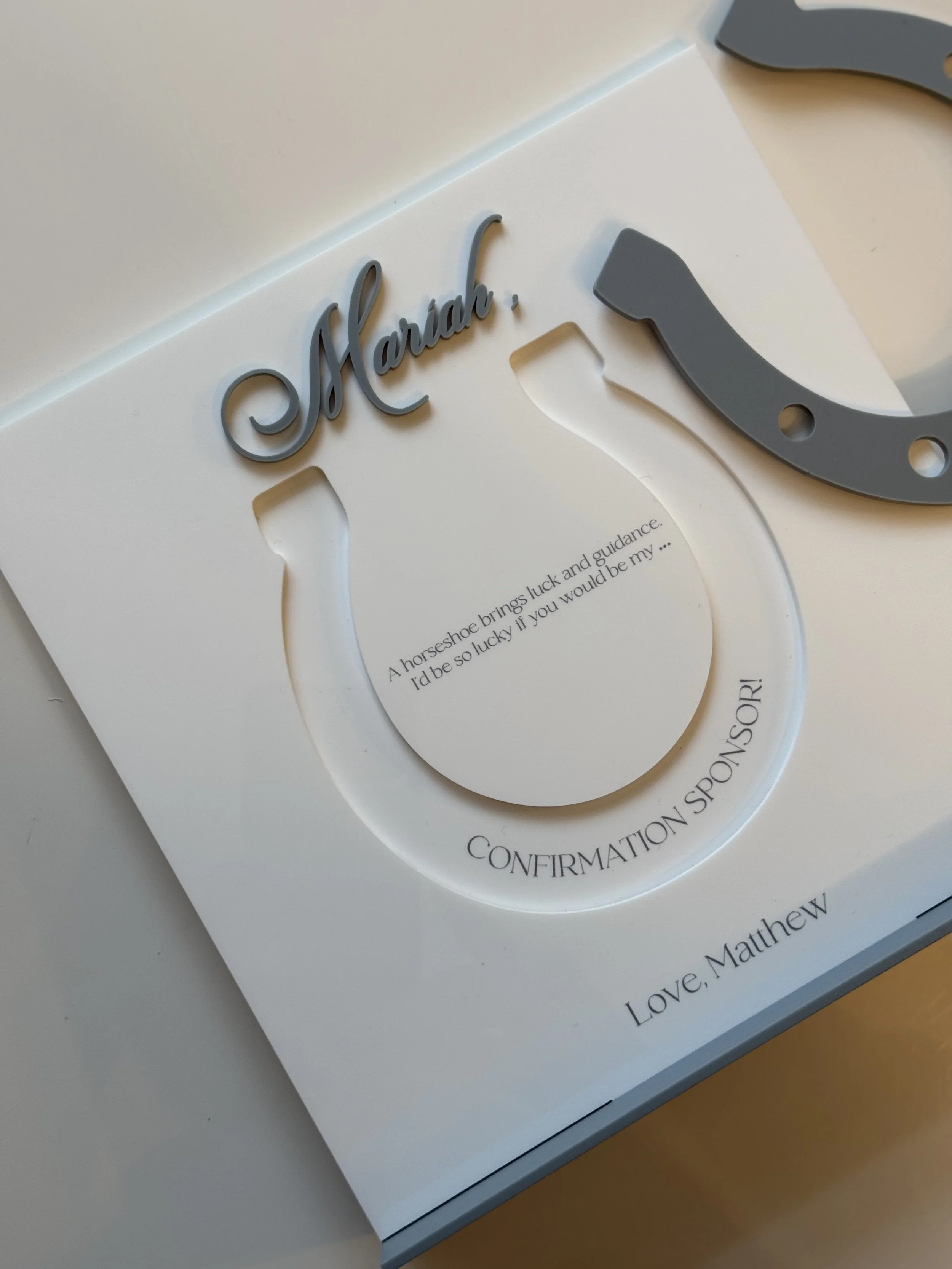 A white card with a horseshoe design and the word 'Mash,' written in cursive, attached at the top. Inside the horseshoe, there is a quote that reads, 'A horseshoe brings luck and guidance. I'd be so lucky if you would be my ...' and at the bottom, th