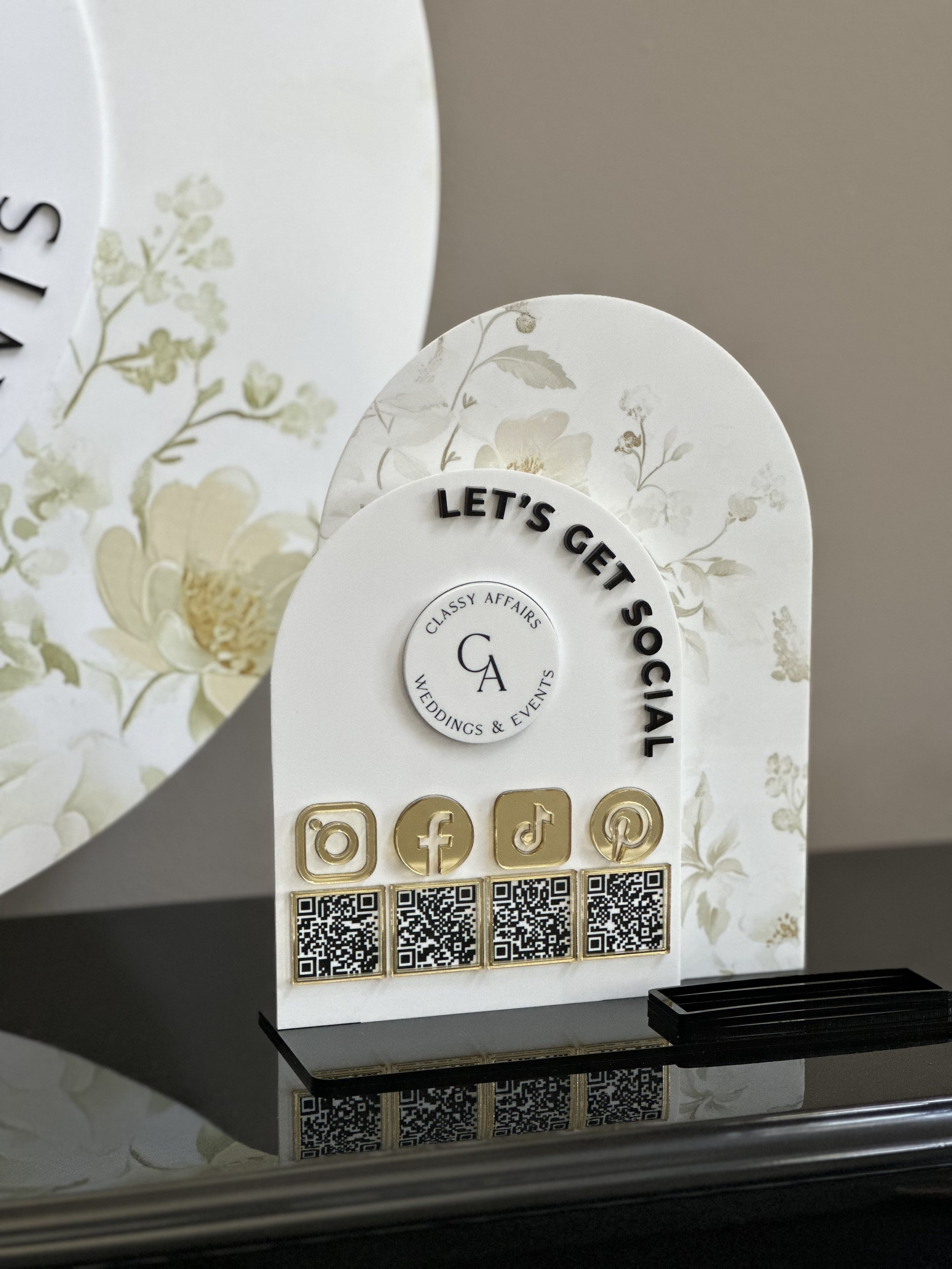 Business card holder with floral design, social media icons, and QR codes, advertising 'Let's Get Social' for weddings and events by Classy Affairs.