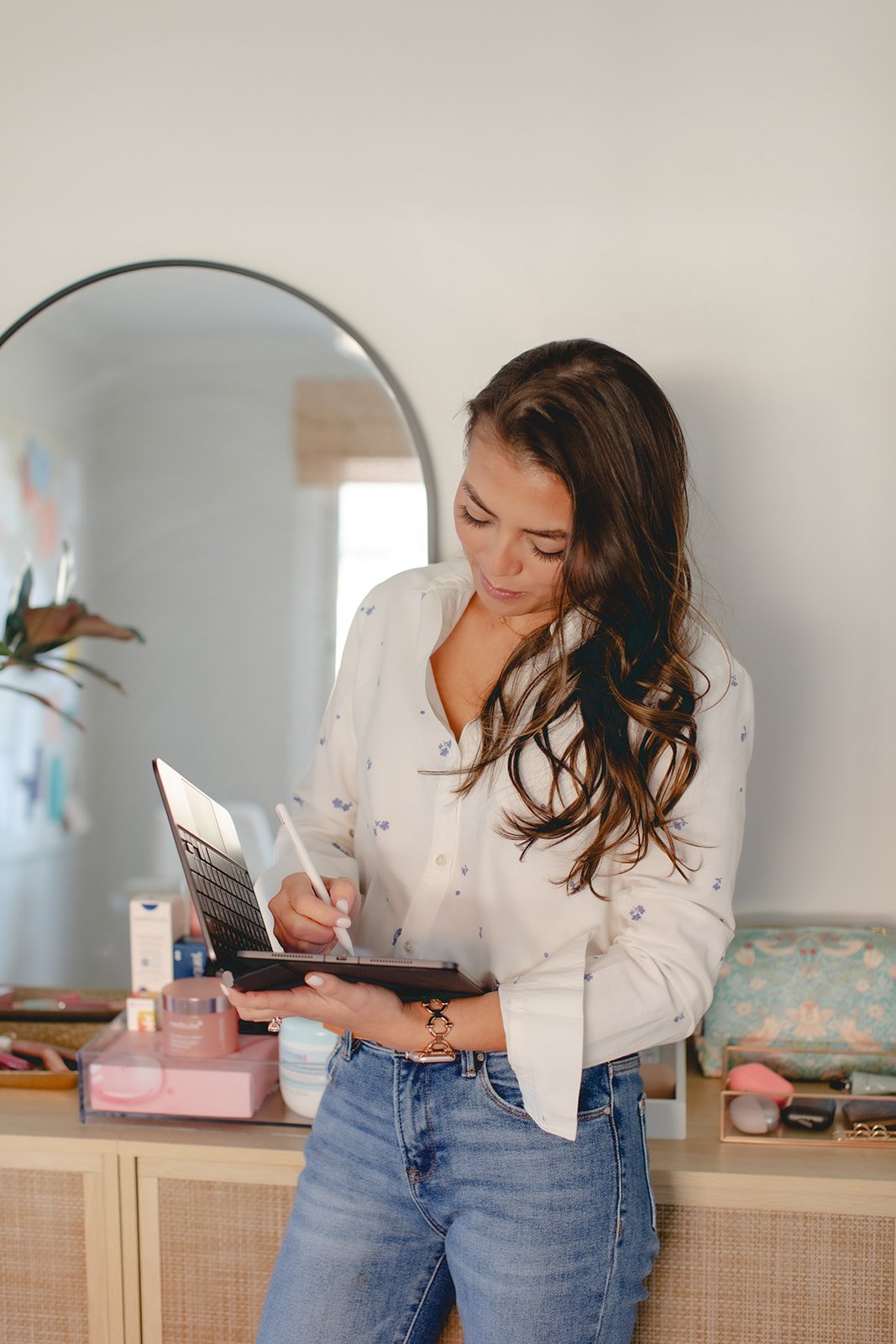 Business owner leaning against a set of cabinets while writing on a computer tablet