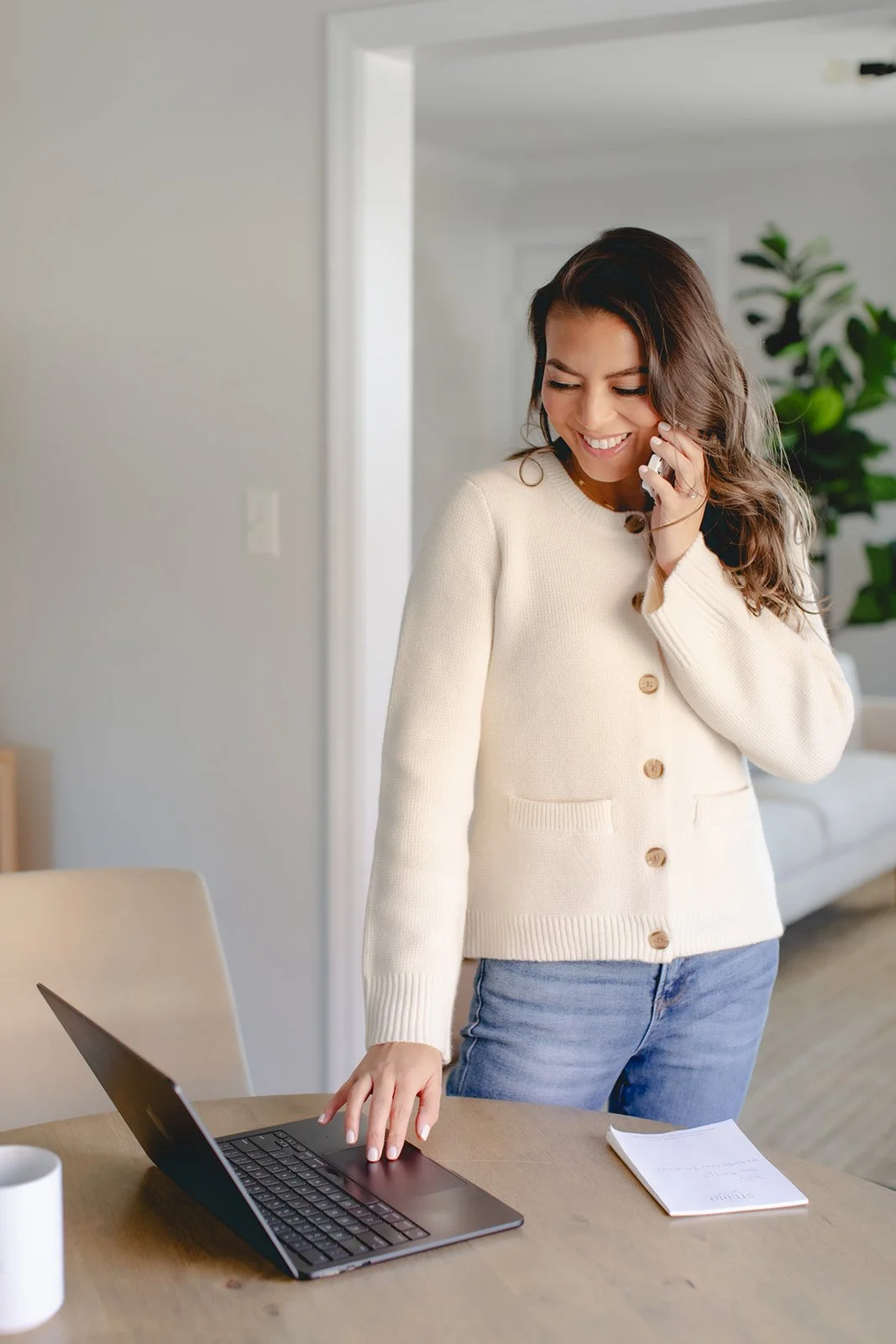 Ad agency owner working while answering the phone and looking at the computer