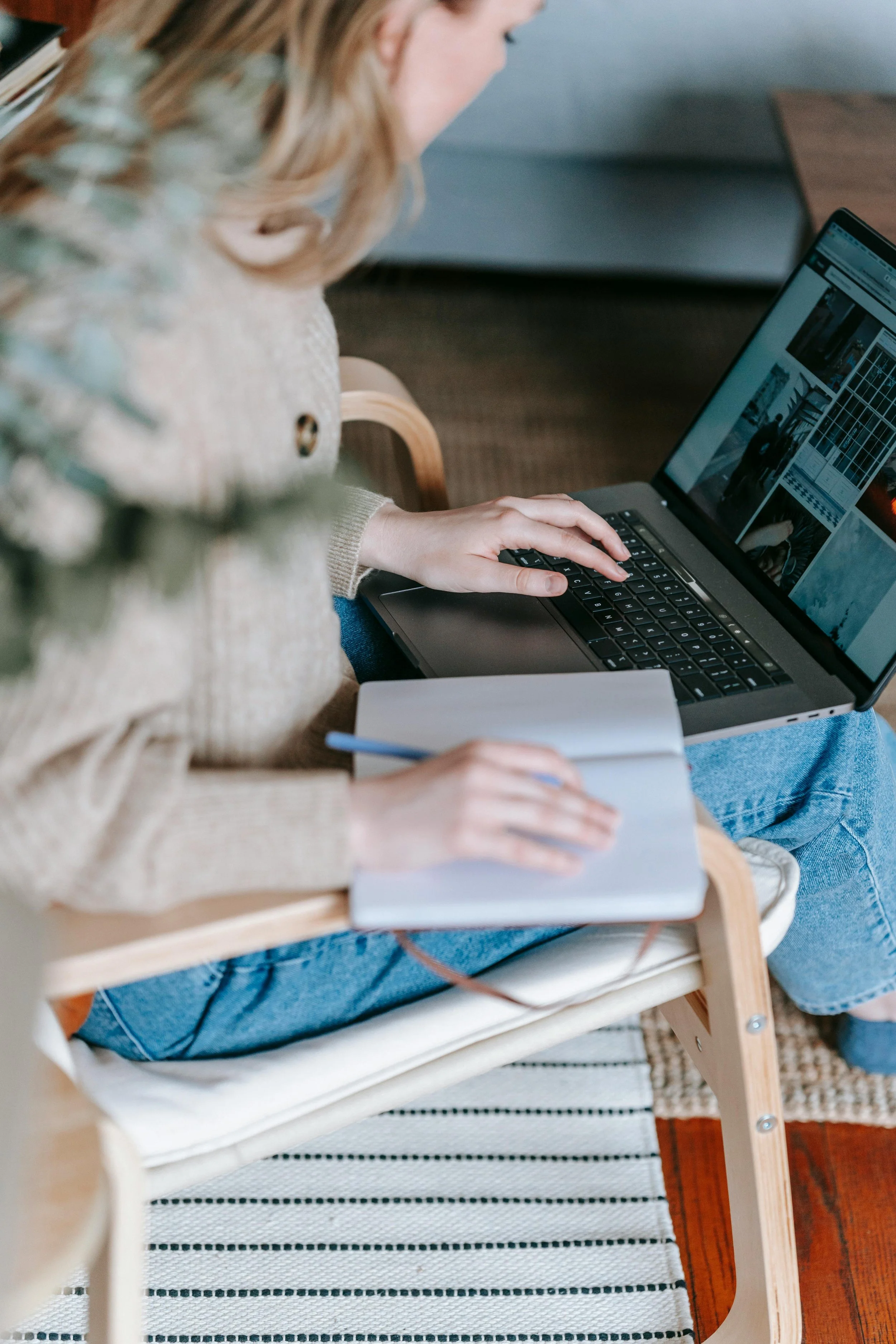 Woman sitting on a chair while working with a computer and notebook