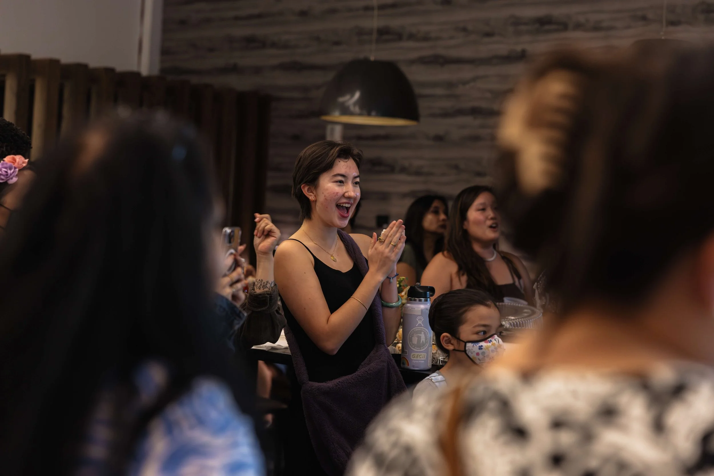 Image of a crowd focused in on a community member clapping at an organizational event.