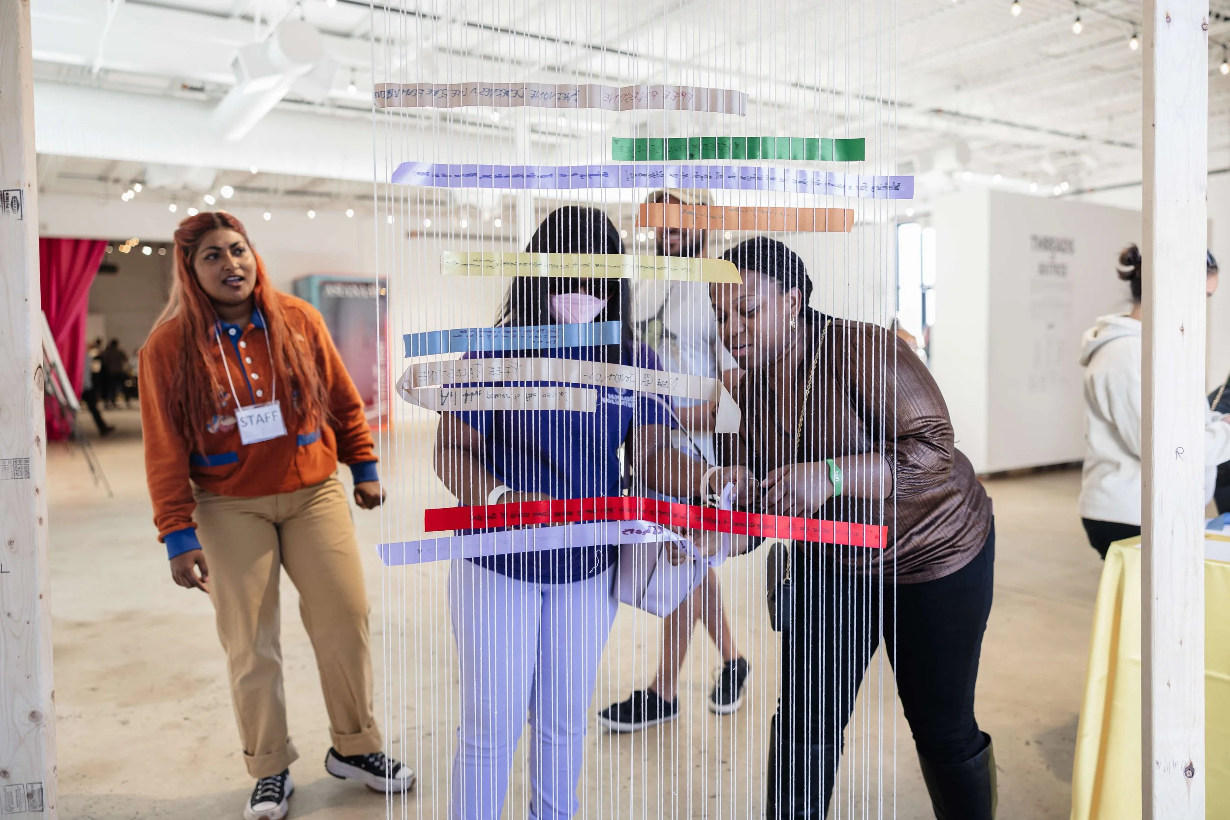 Artist Sayma Hossein facilitating an interactive art installation with community members engaging.