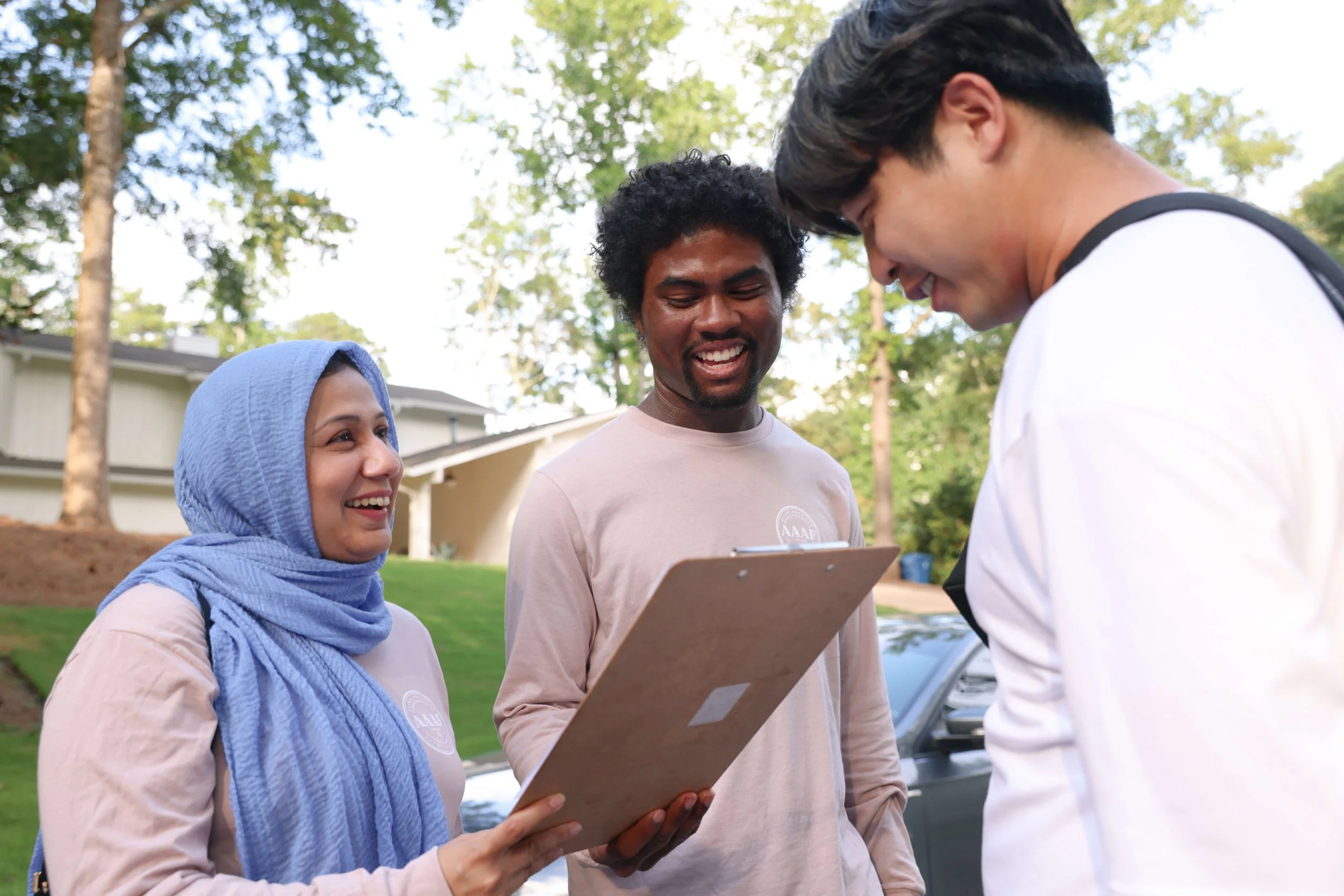 Two canvassers, one with a clipboard smiling and talking to a community member.