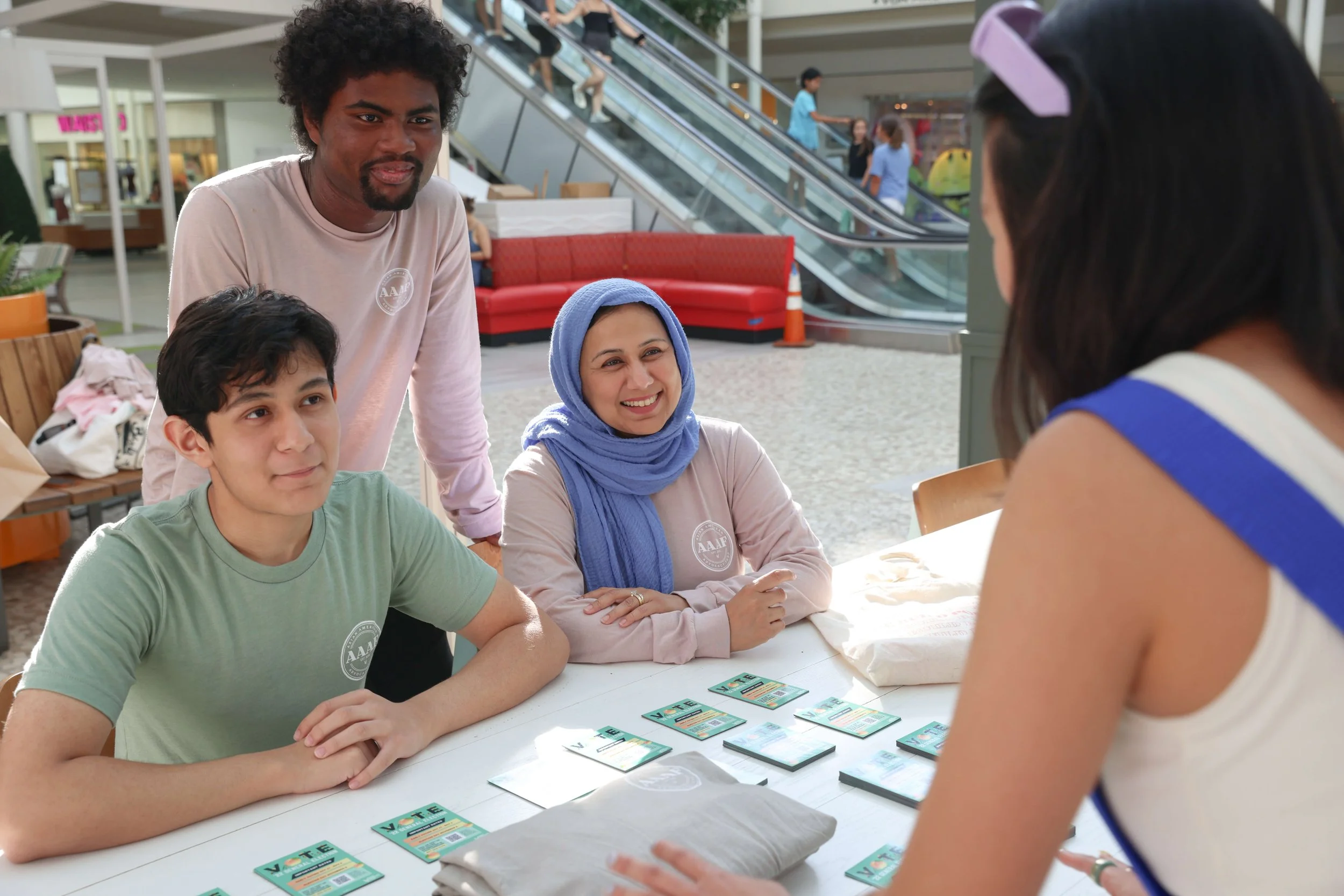 Three staff members with tabling with organizing materials in front of them and talking to a community member.
