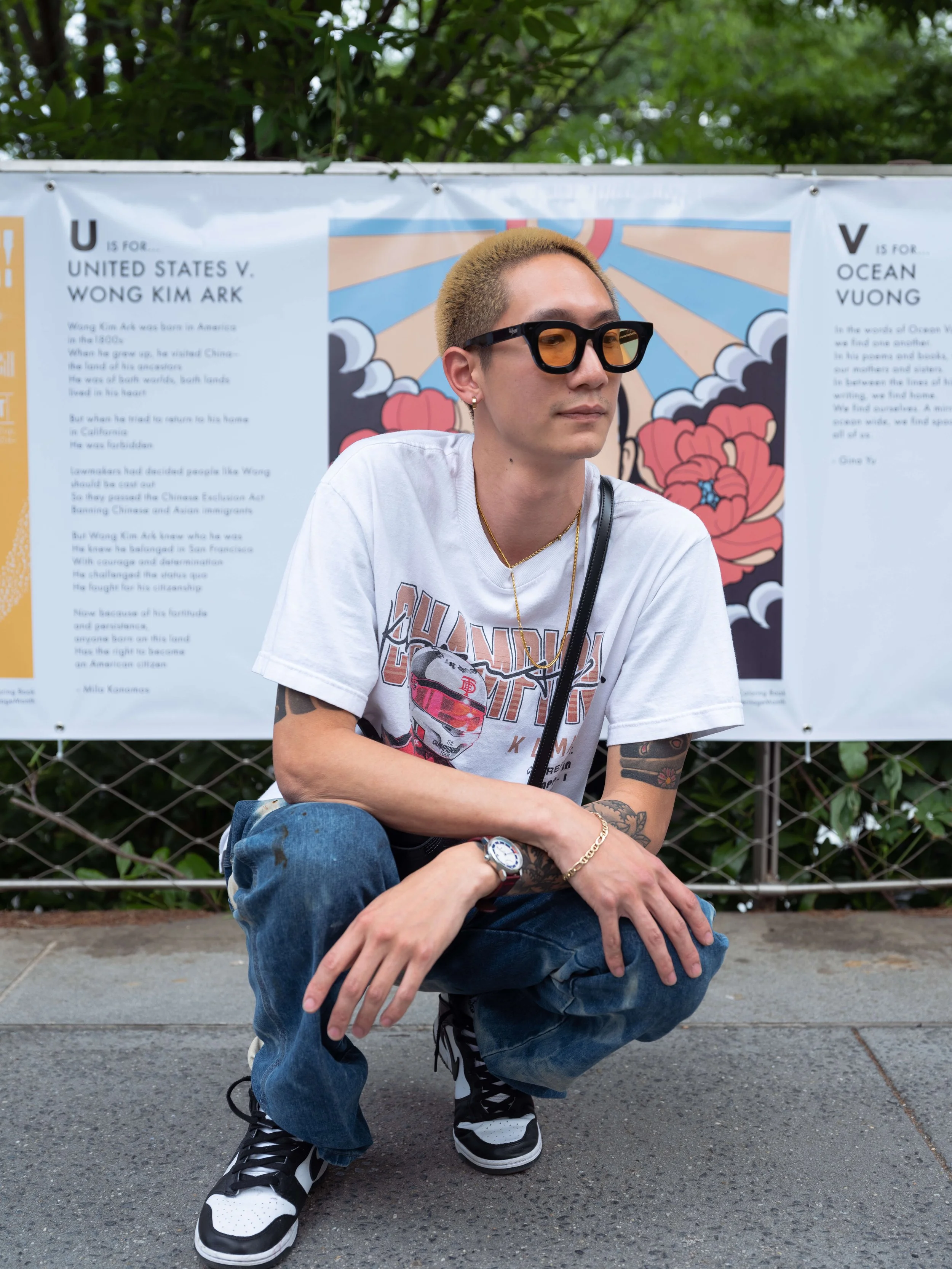 Artist Andrew Blooms posing in front of his illustration from The ABCs of AAPIs art exhibit.