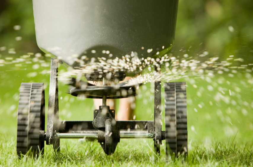 Lawn mower cutting grass with grass clippings flying in the air.