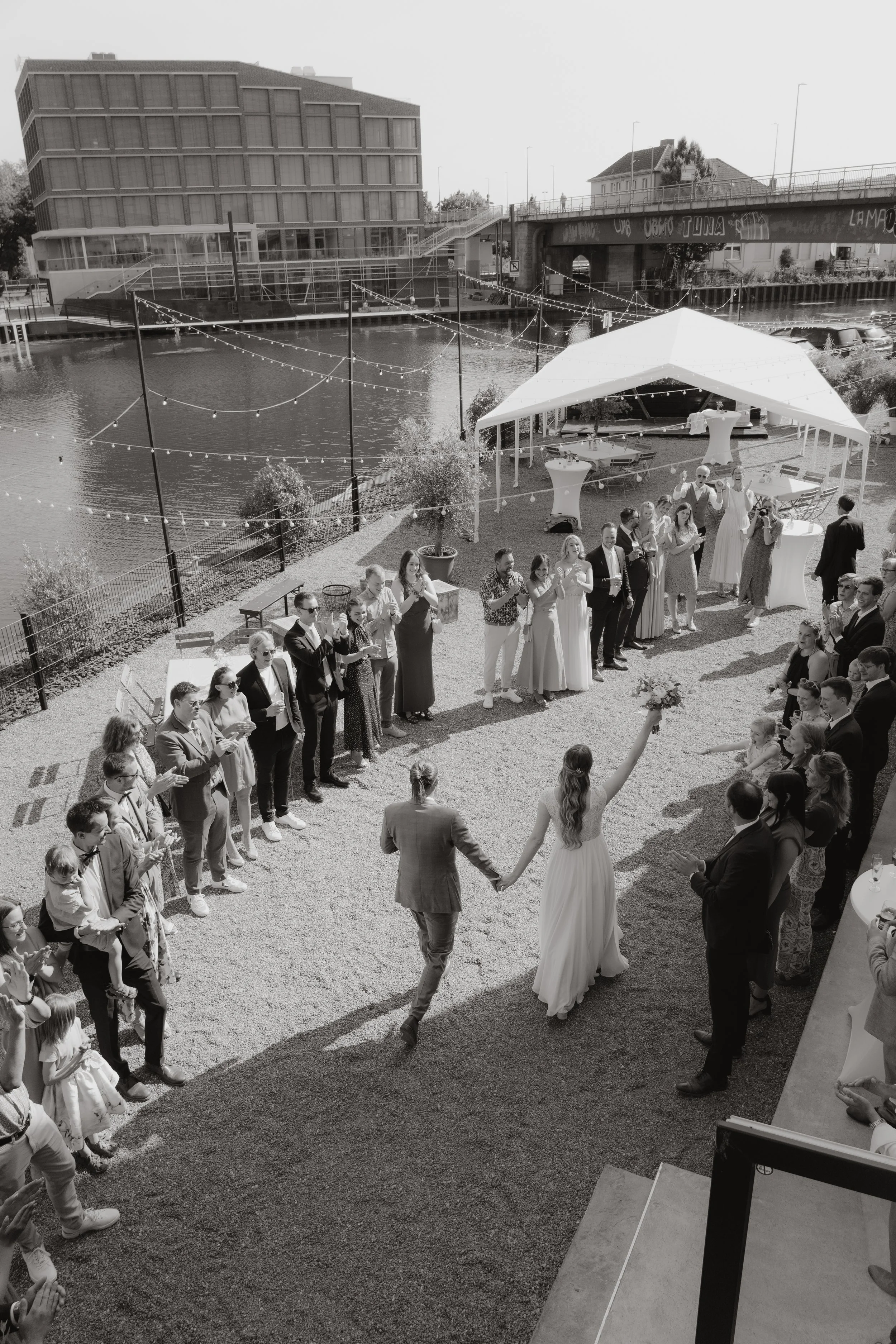 Hochzeit im Freien mit Brautpaar, Gästen und Dekorationen am Wasser