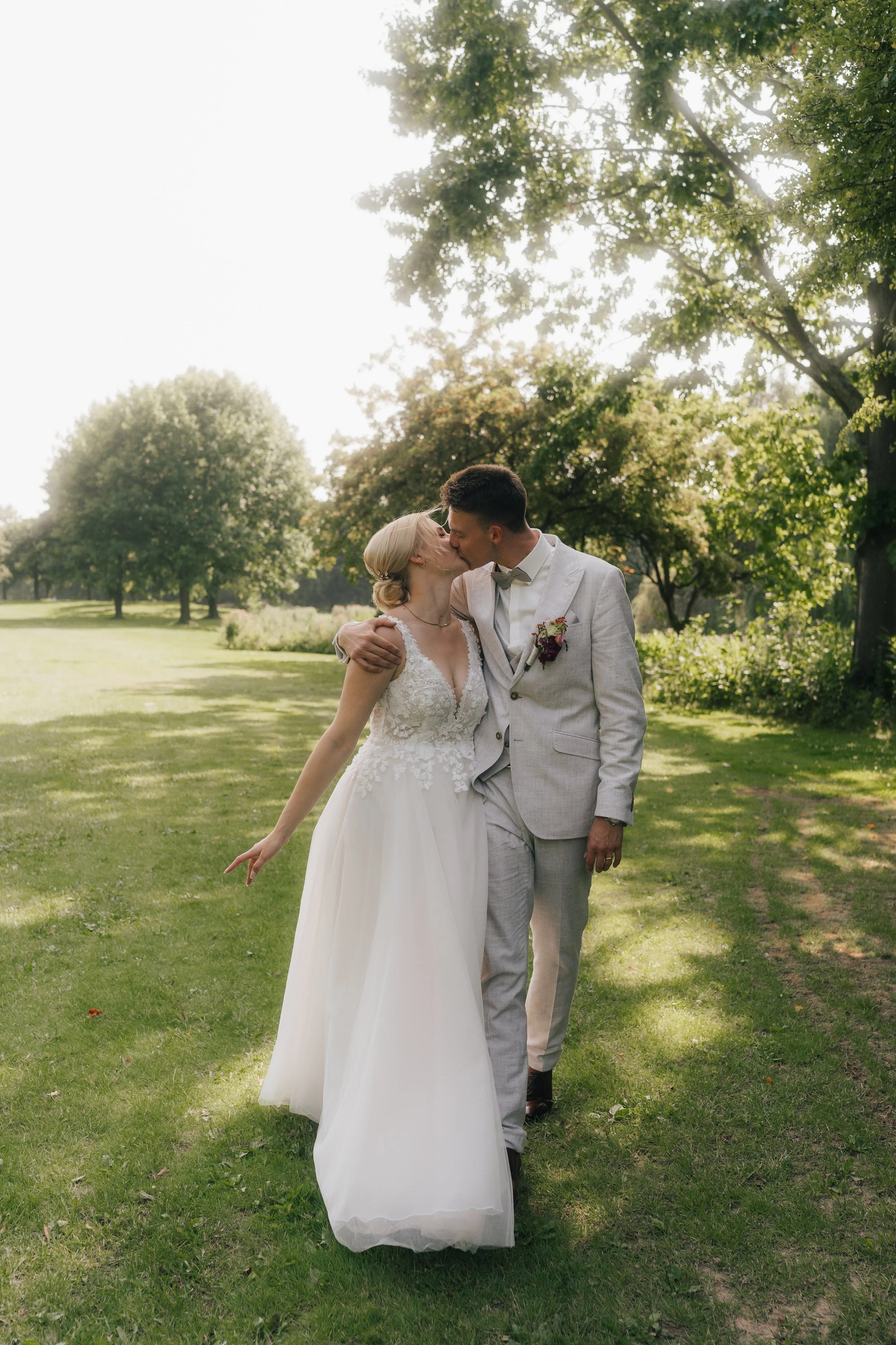 Braut und Bräutigam küssen sich im Park bei Sonnenschein an ihrer Hochzeit in Leverkusen