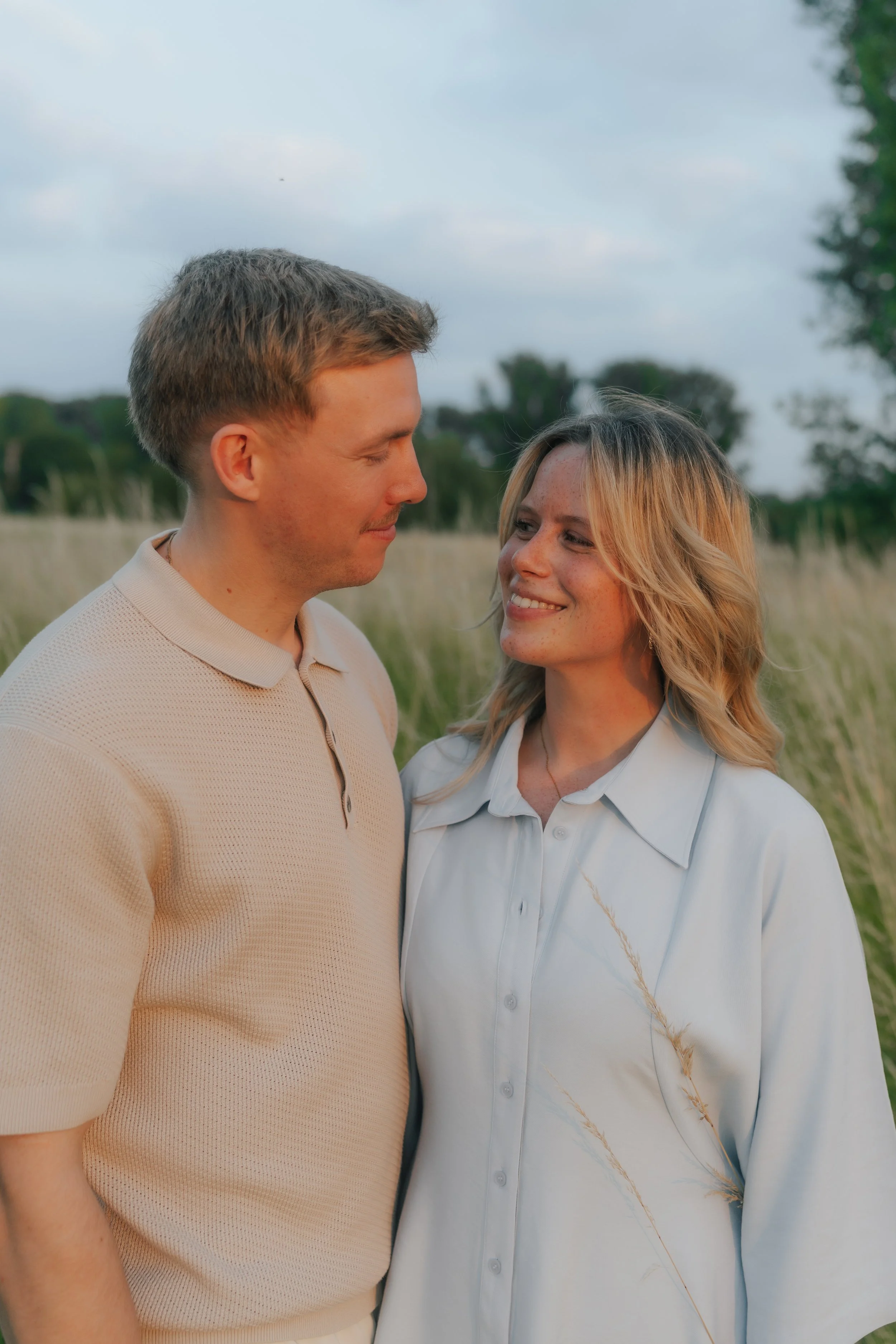 Ein lachendes Paar steht bei ihrem Paarshooting im Feld