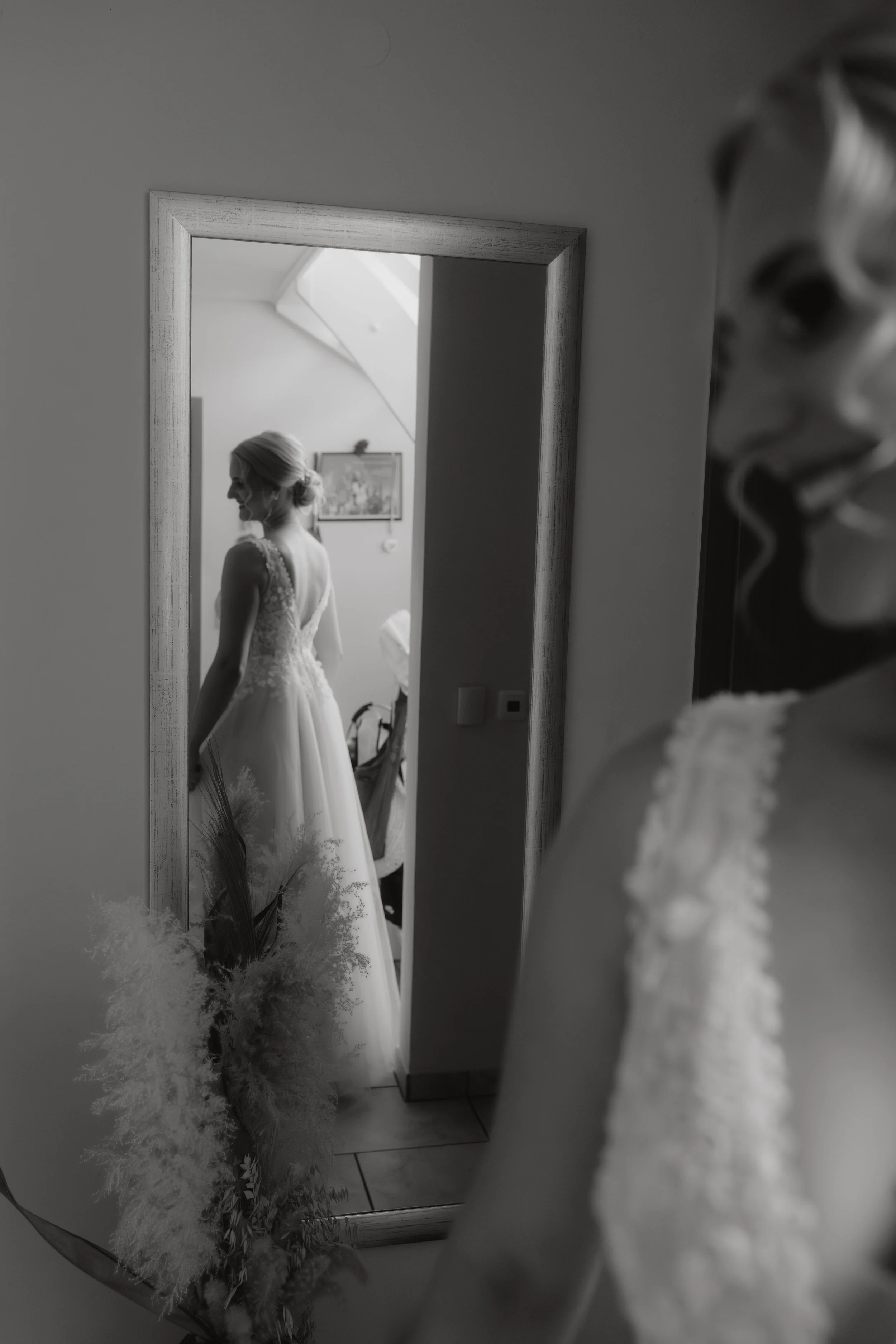 Eine Braut steht vor einem Spiegel, während sie sich auf ihre Hochzeit vorbereitet. Getting Ready mit ihren Brautjungfern