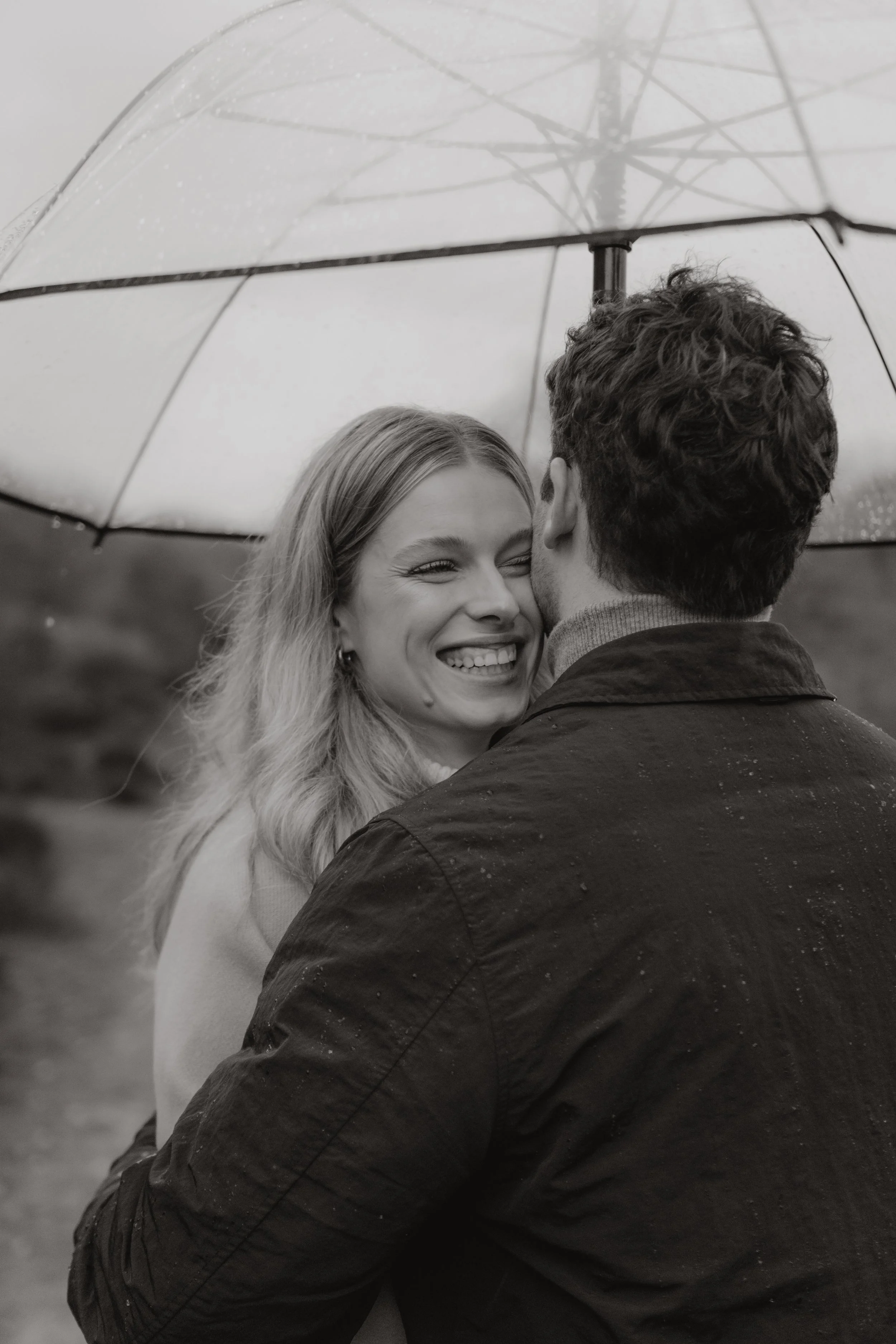 Ein lachendes Paar unter einem Regenschirm im Regen, schwarz-weißes Foto