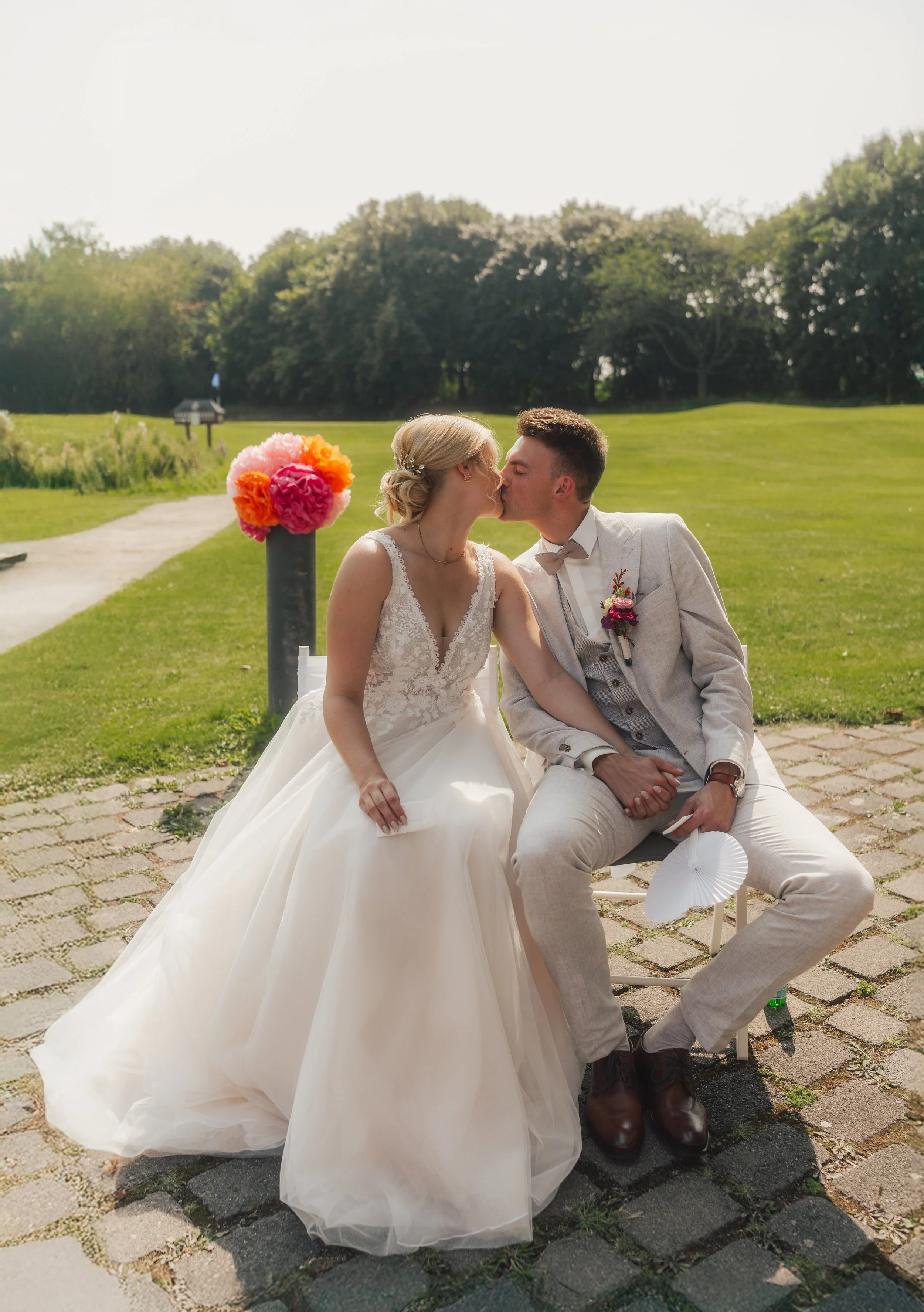 Ein Brautpaar, das sich küsst, im Freien auf einer gepflasterten Fläche bei sonnigem Wetter an ihrer Freien Trauung