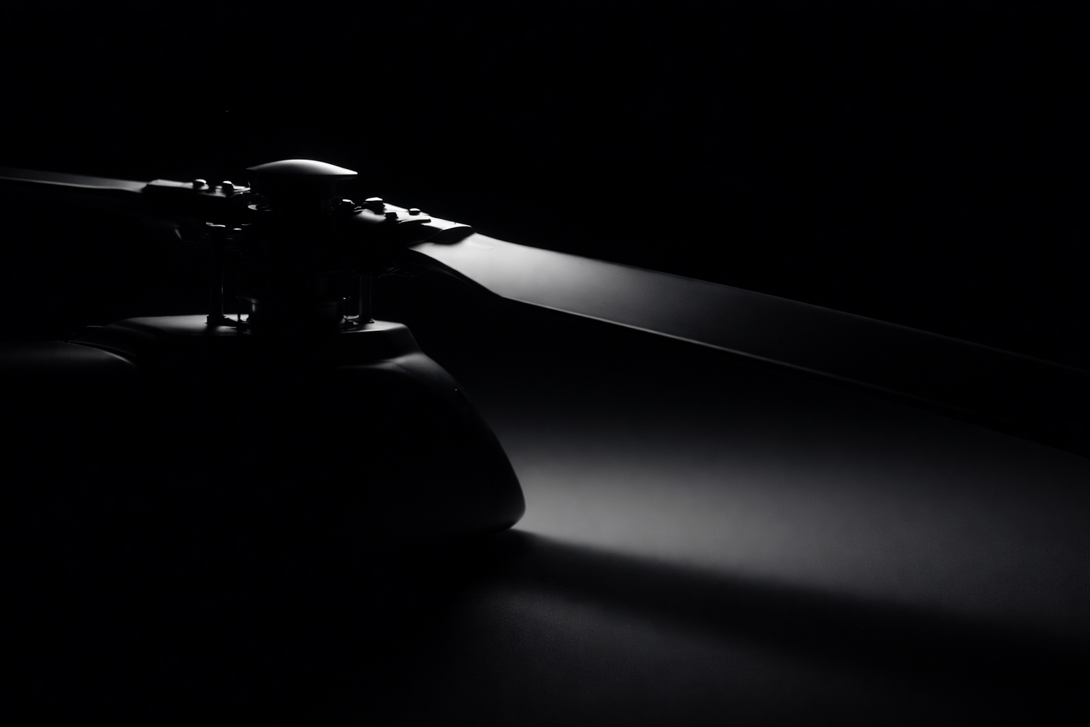 Close-up of a drone rotor blade with low lighting, creating shadows and highlights on the blade and motor.