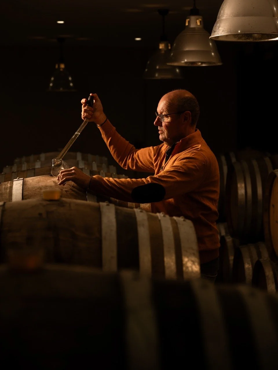 Eric Poissinet du champagne Poissinet dans une cave à vin en train de déguster du vin dans une ambiance chaleureuse et tamisée. Photo prise par Théo WALLYN, TheWallPhoto.