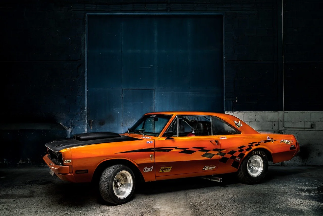 Voiture de course orange dans un garage sombre. Photo prise par Théo WALLYN, TheWallPhoto.