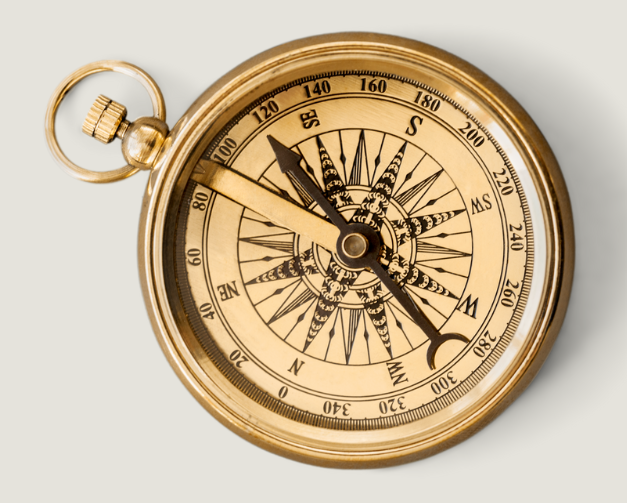 A vintage gold pocket compass with a detailed face, showing cardinal directions and a decorative star pattern at the center, placed on a light background.