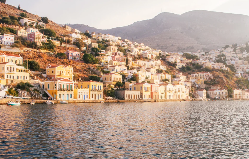 Colorful houses on a hillside overlooking a body of water at sunset
