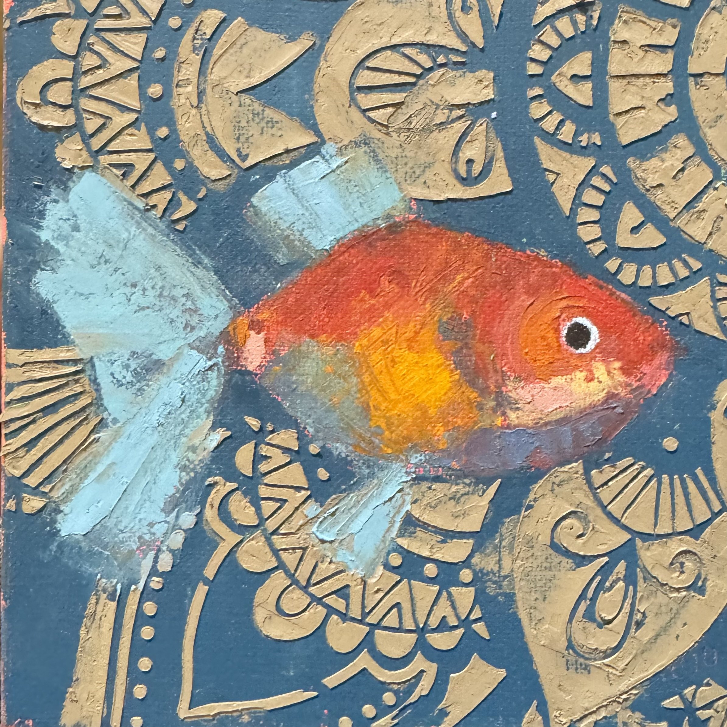 An abstract painting of a goldfish with a blue body and orange, yellow, and red accents, surrounded by gold decorative patterns on a dark background.