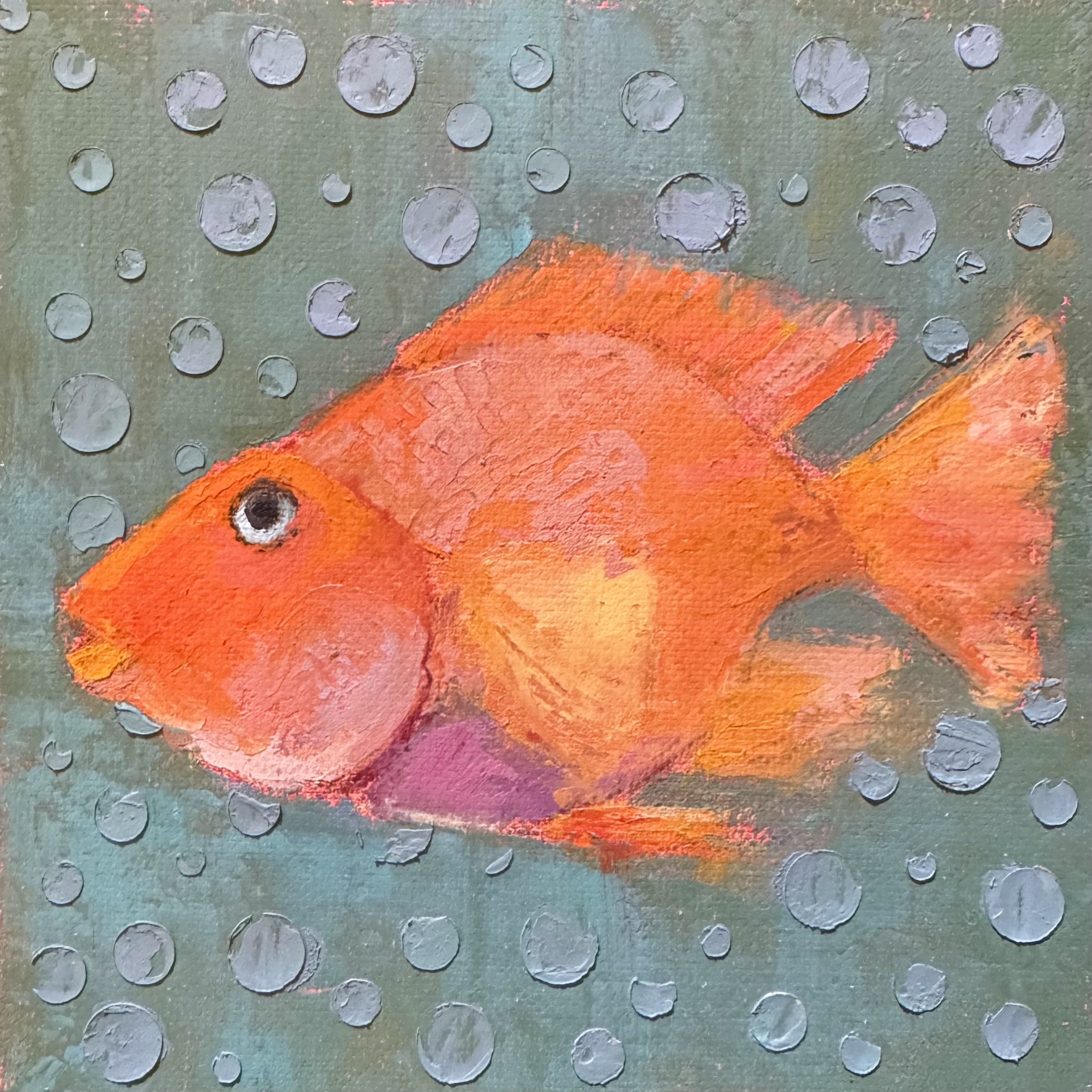 An orange fish with black eye swimming amidst blue and purple bubbles in water.