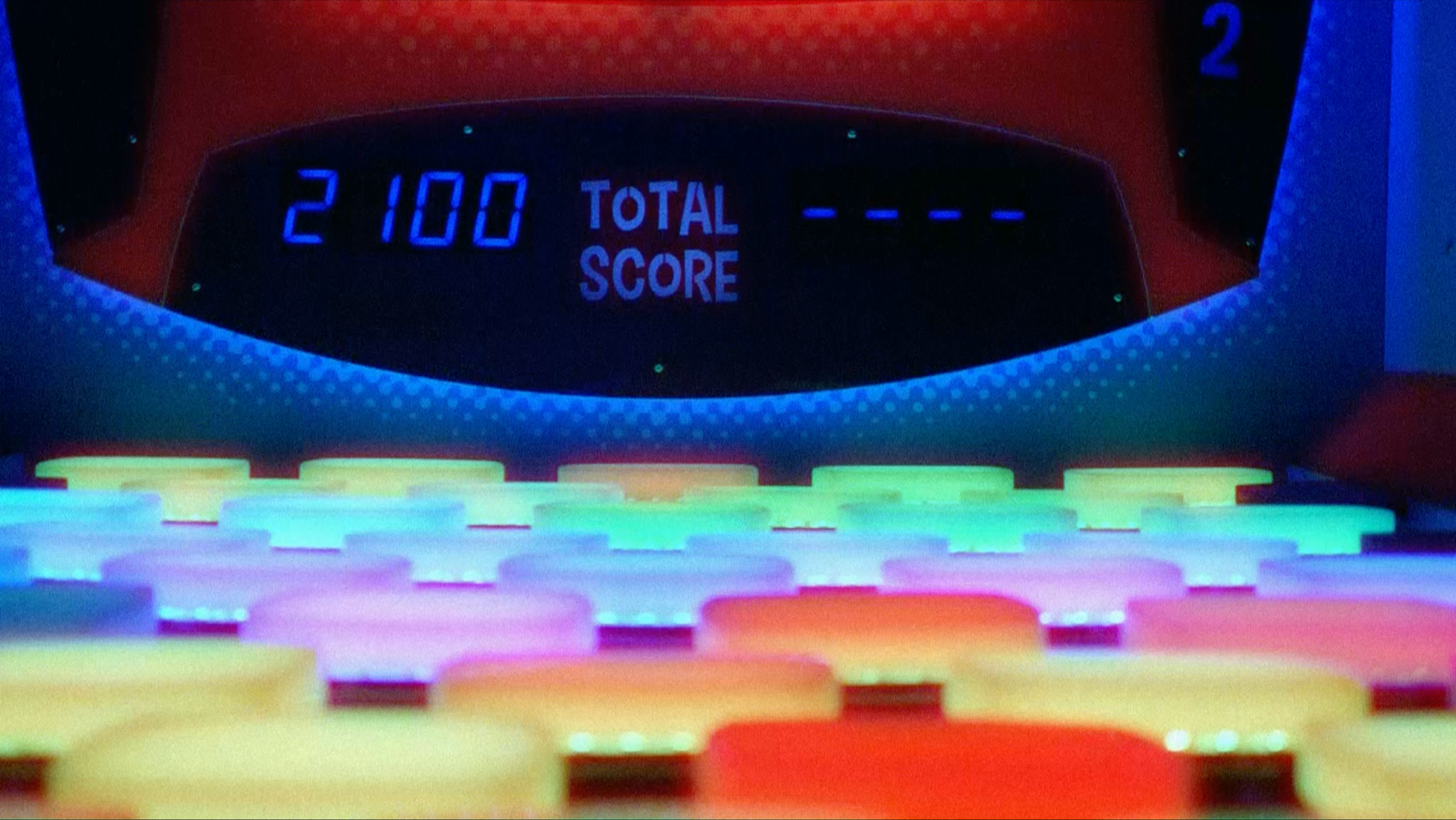 close up of a retro-style video game console with colorful buttons and a blue digital readout that says "2100 total score"