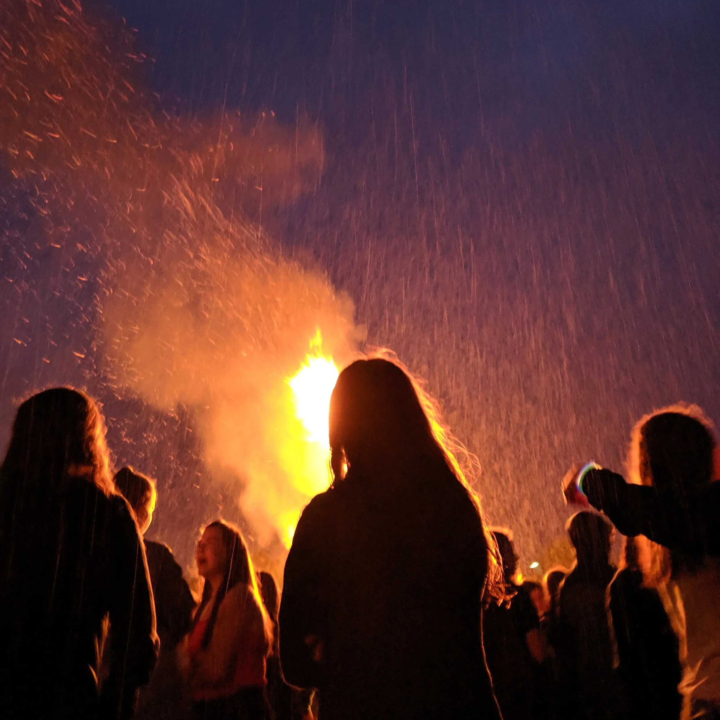People watching a bonfire at night during a celebration.