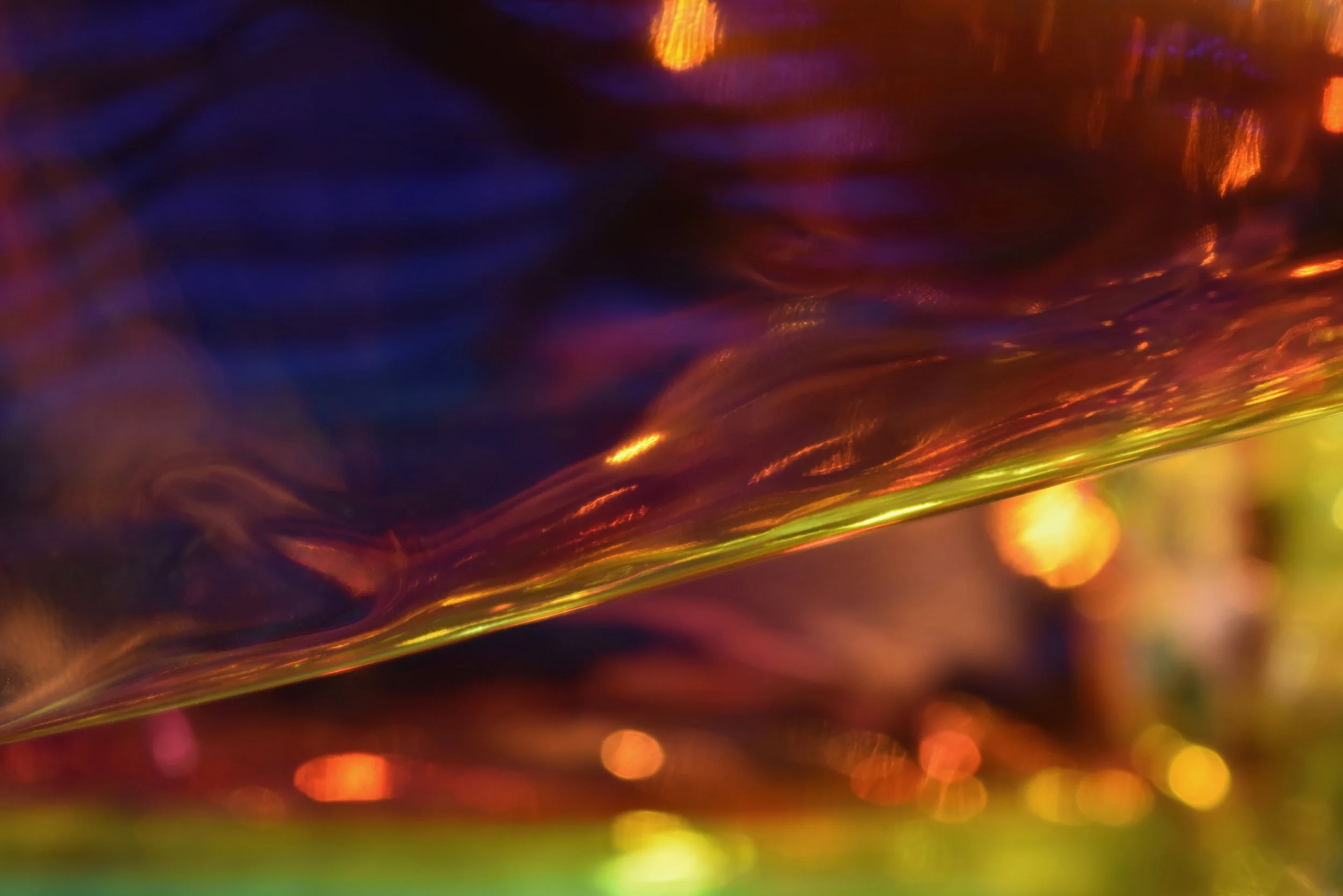 Abstract image of a plasticine material, glimmering in orange, yellow, and midnight blue hues.