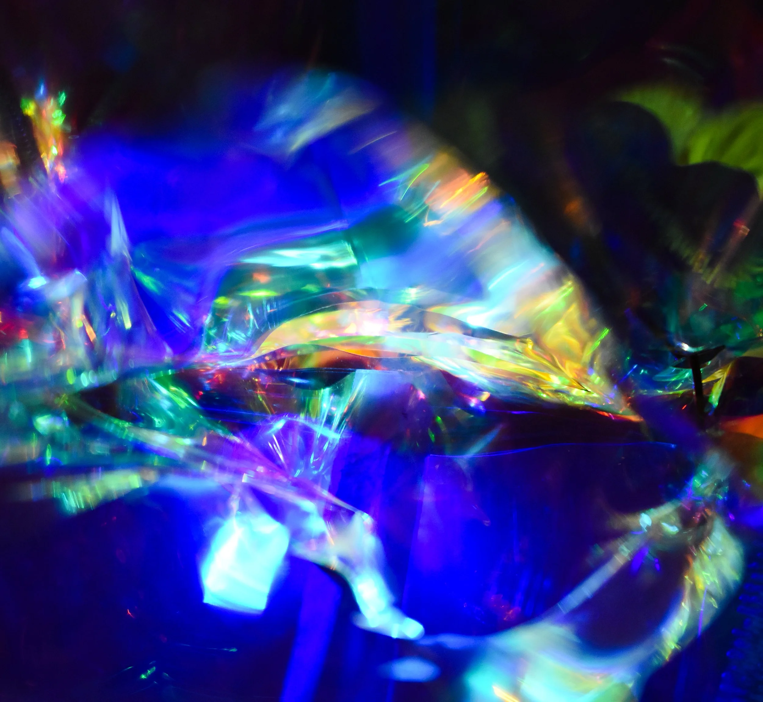 Frenzied, abstract image of a formation of multicolored light reflections popping out from a dark background