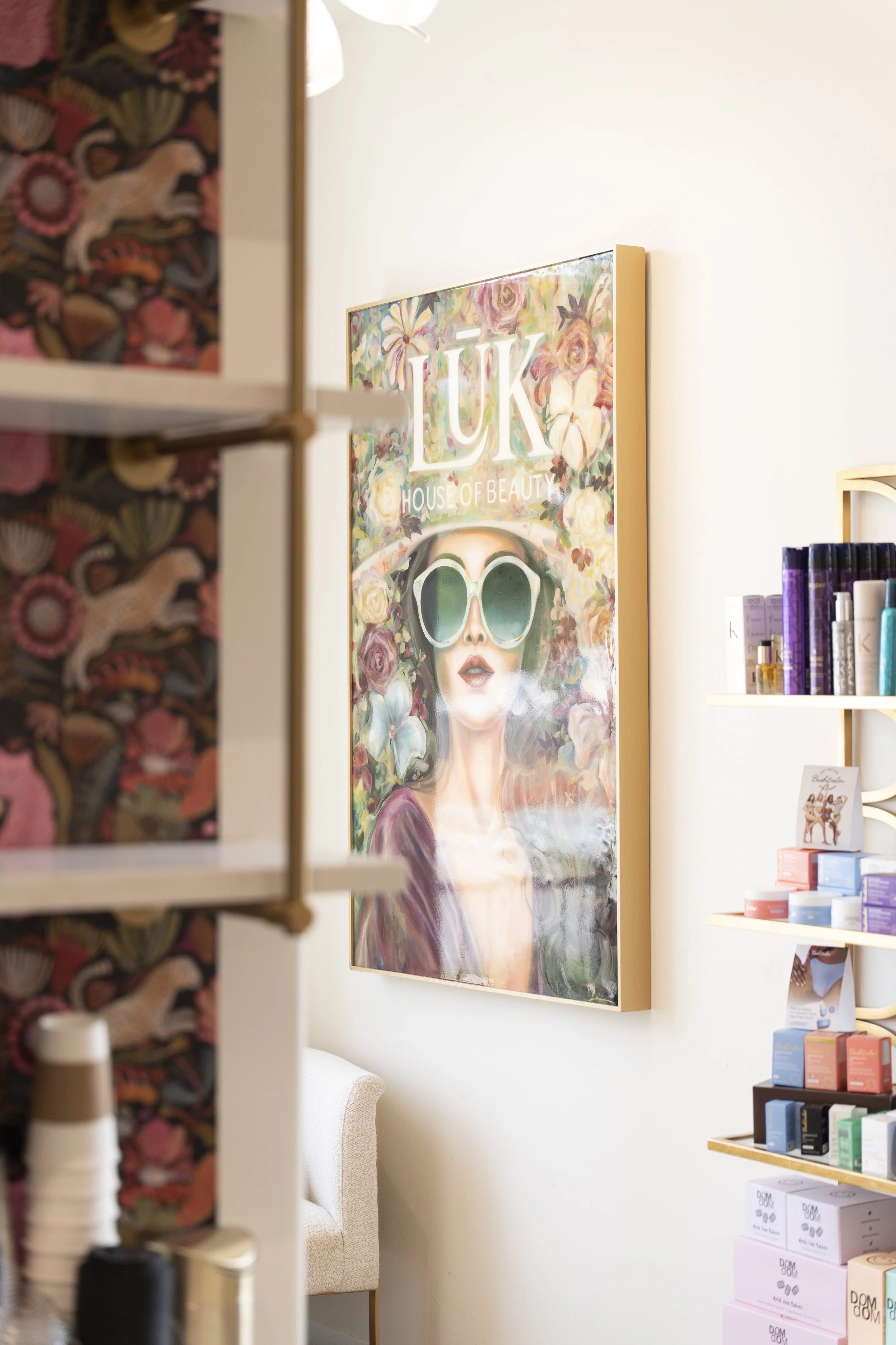 Interior of LŪK House of Beauty salon with colorful artwork and shelves of professional haircare products