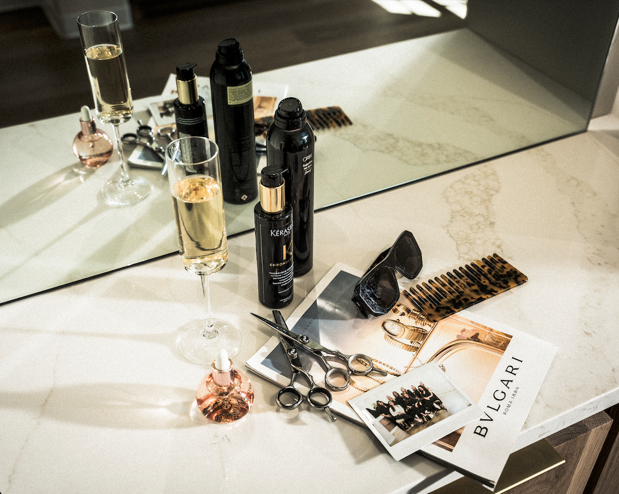 Luxury salon flat lay with professional hair tools, premium haircare products, and champagne in modern beauty studio
