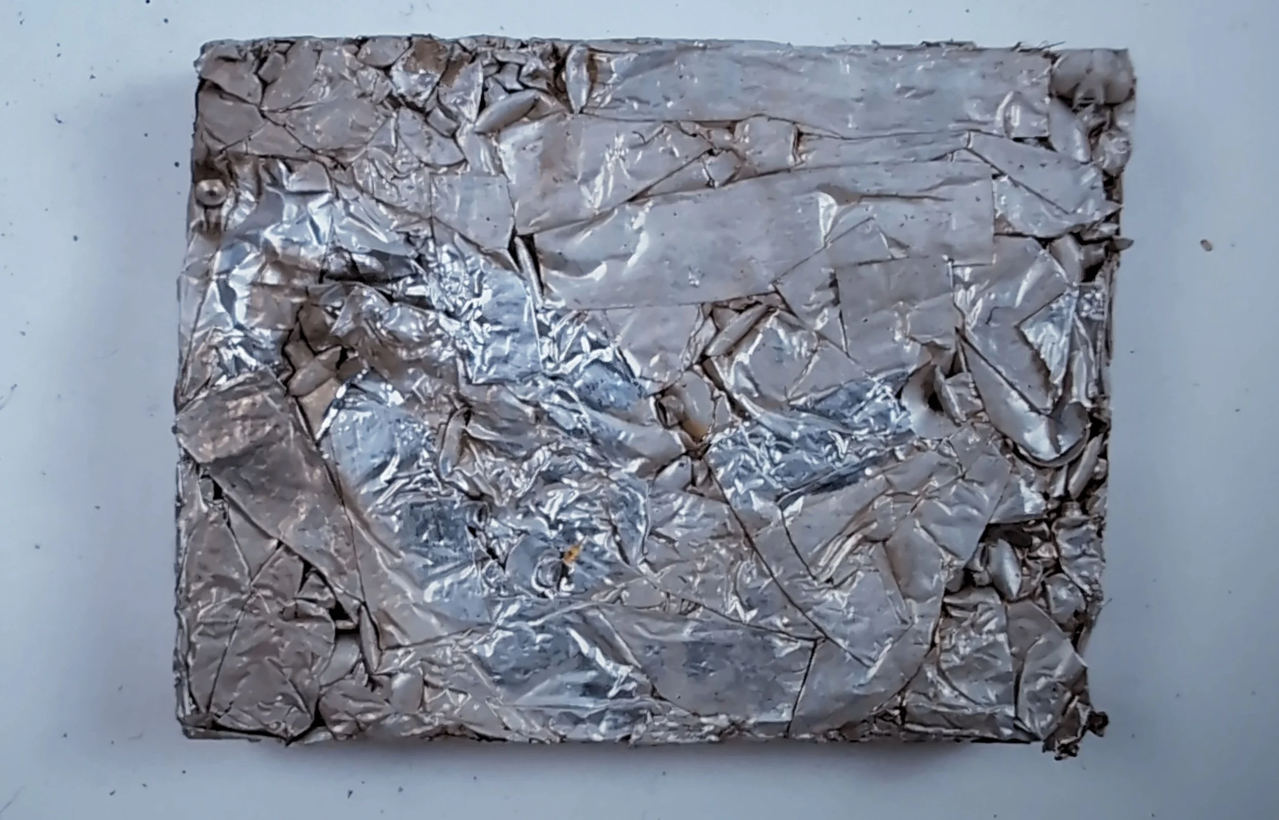 A crumpled piece of aluminum foil placed on a plain surface.