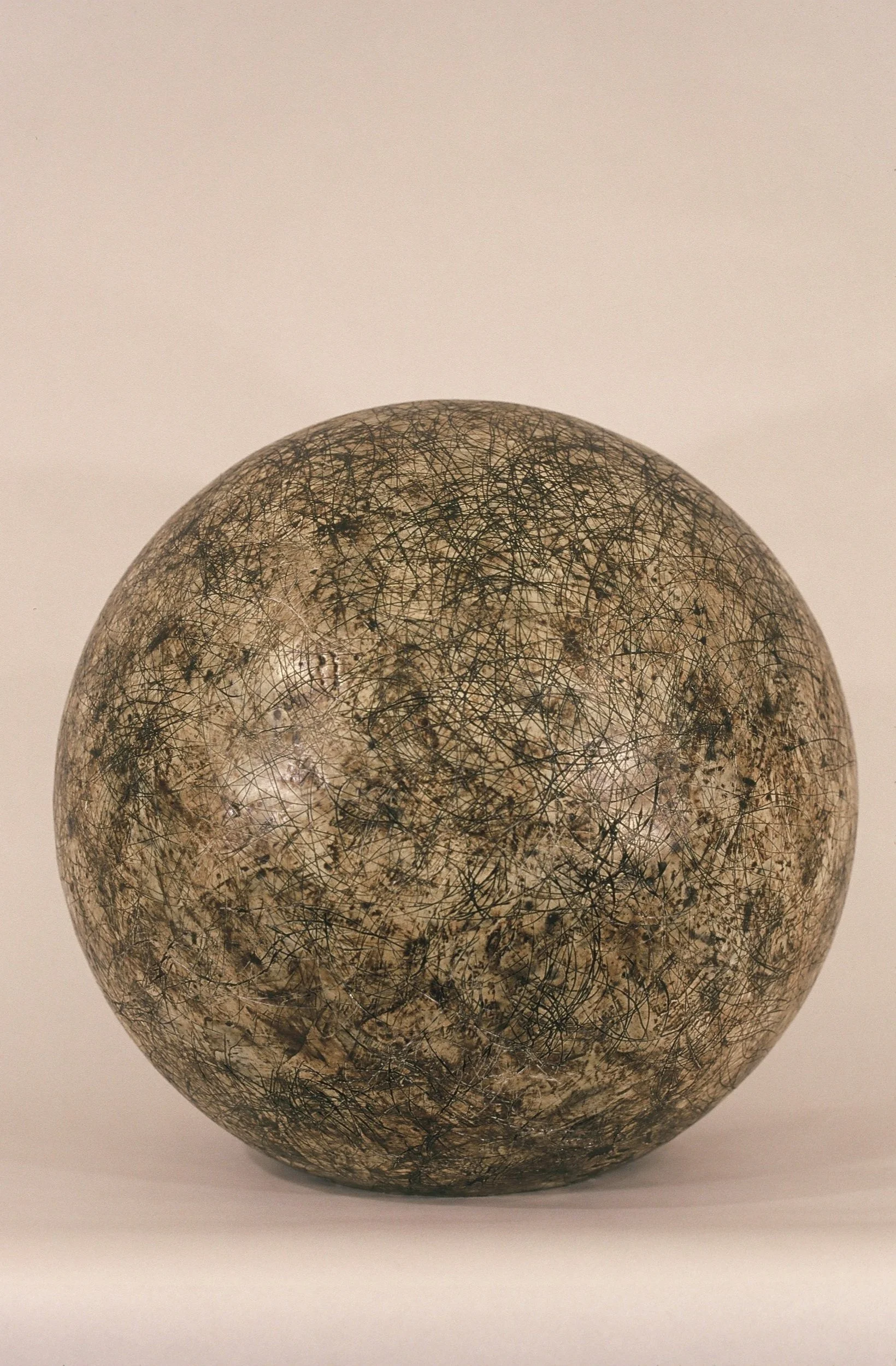 A spherical object with an artistic, marbled pattern of black and beige lines and textures.