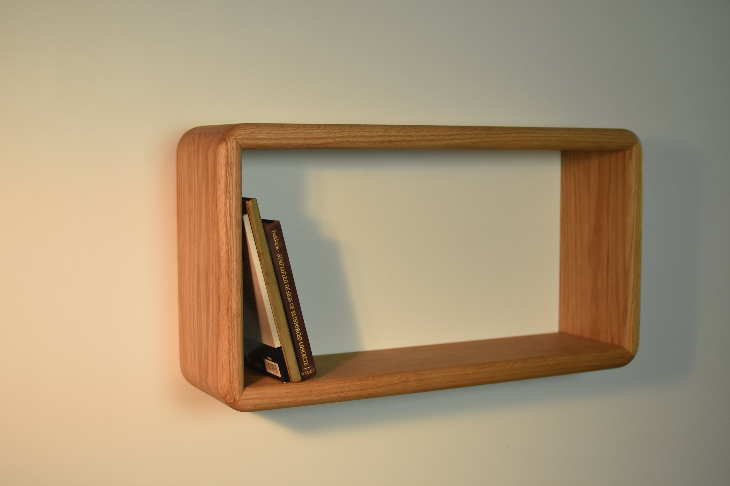 Wooden bookshelf with a few books leaning against the side and space for additional books.