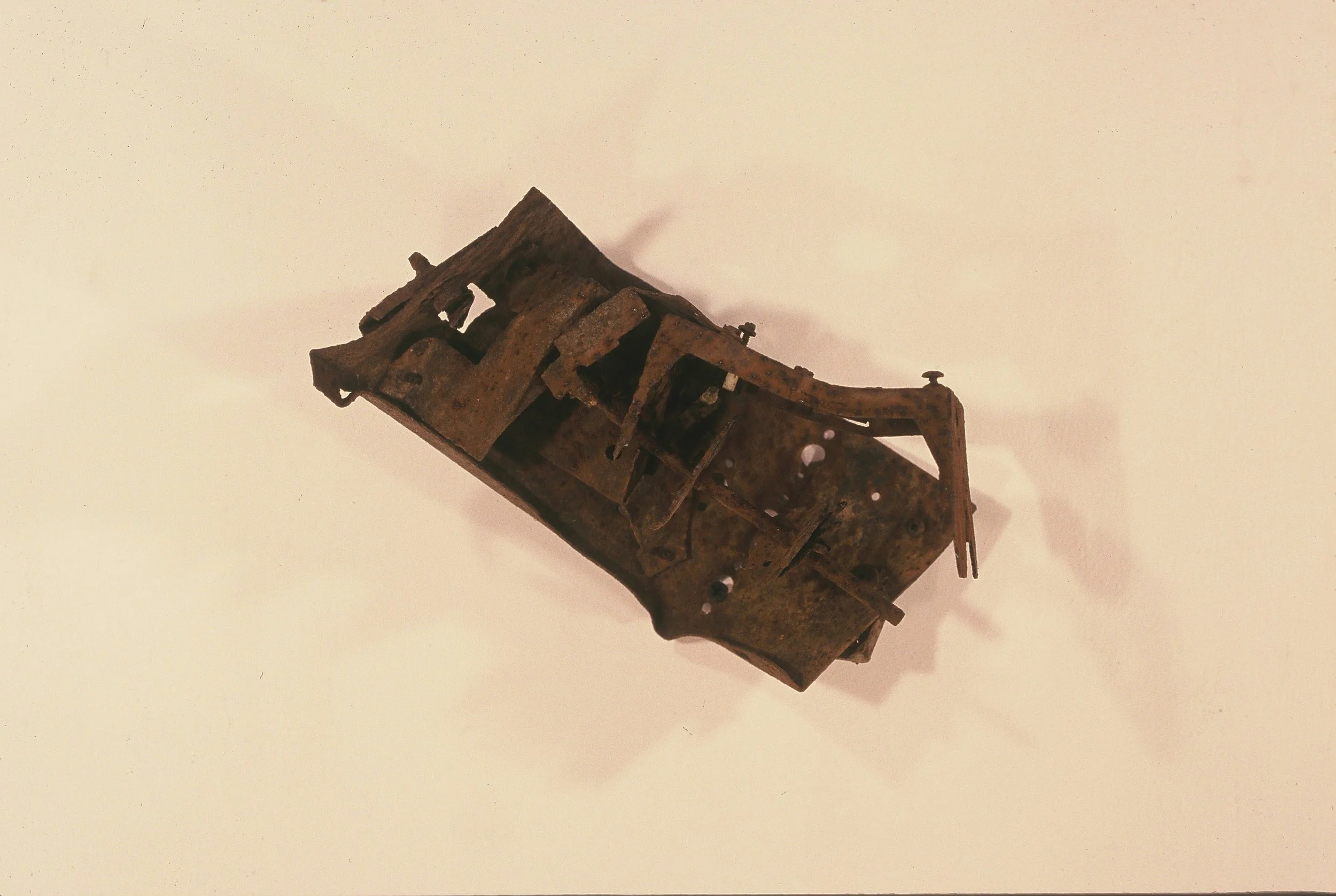 A rusted metal mechanical part with various components and openings, possibly an old machine or clock part.