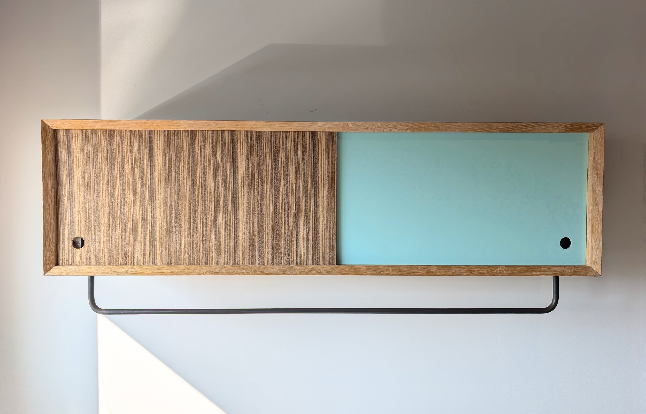 Custom wall-mounted cabinet with sliding doors in solid wood and painted finish, designed and fabricated by Parallel Studios near Kingston, Ontario.