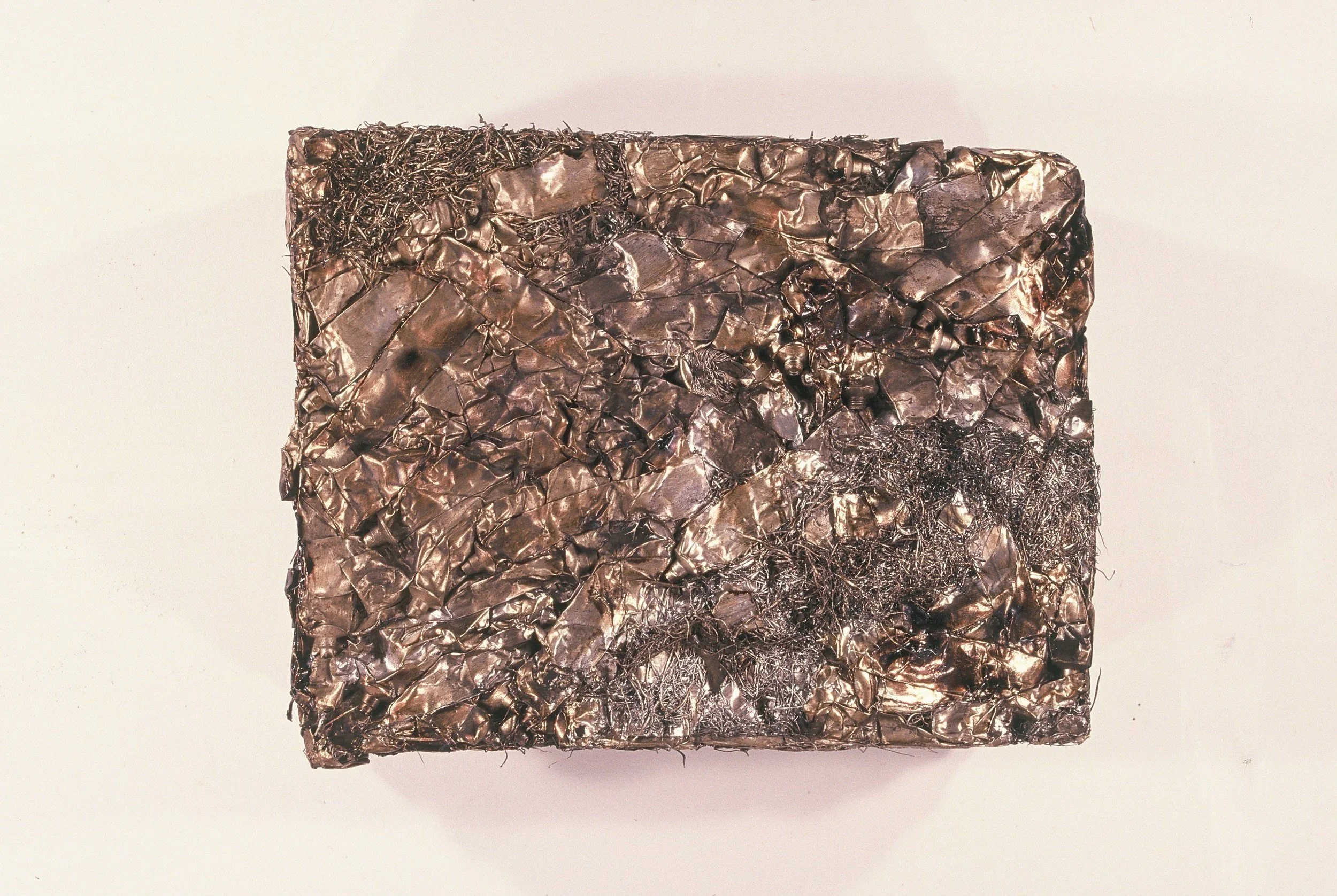 A bar of soap with a crinkled metallic surface in shades of dark gray and silver.