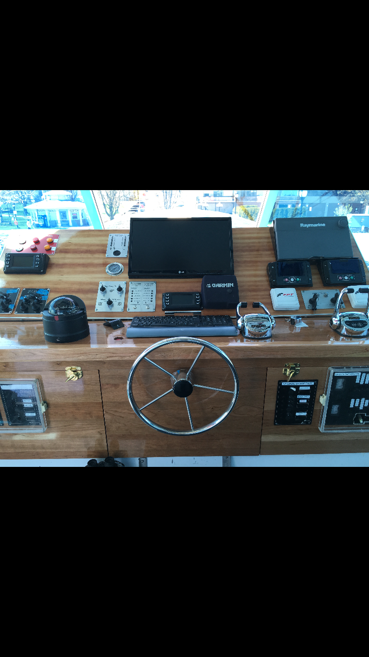 Navigation and marine control equipment on a boat's helm station, including a steering wheel, GPS, radar, autopilot controls, and electronic displays.