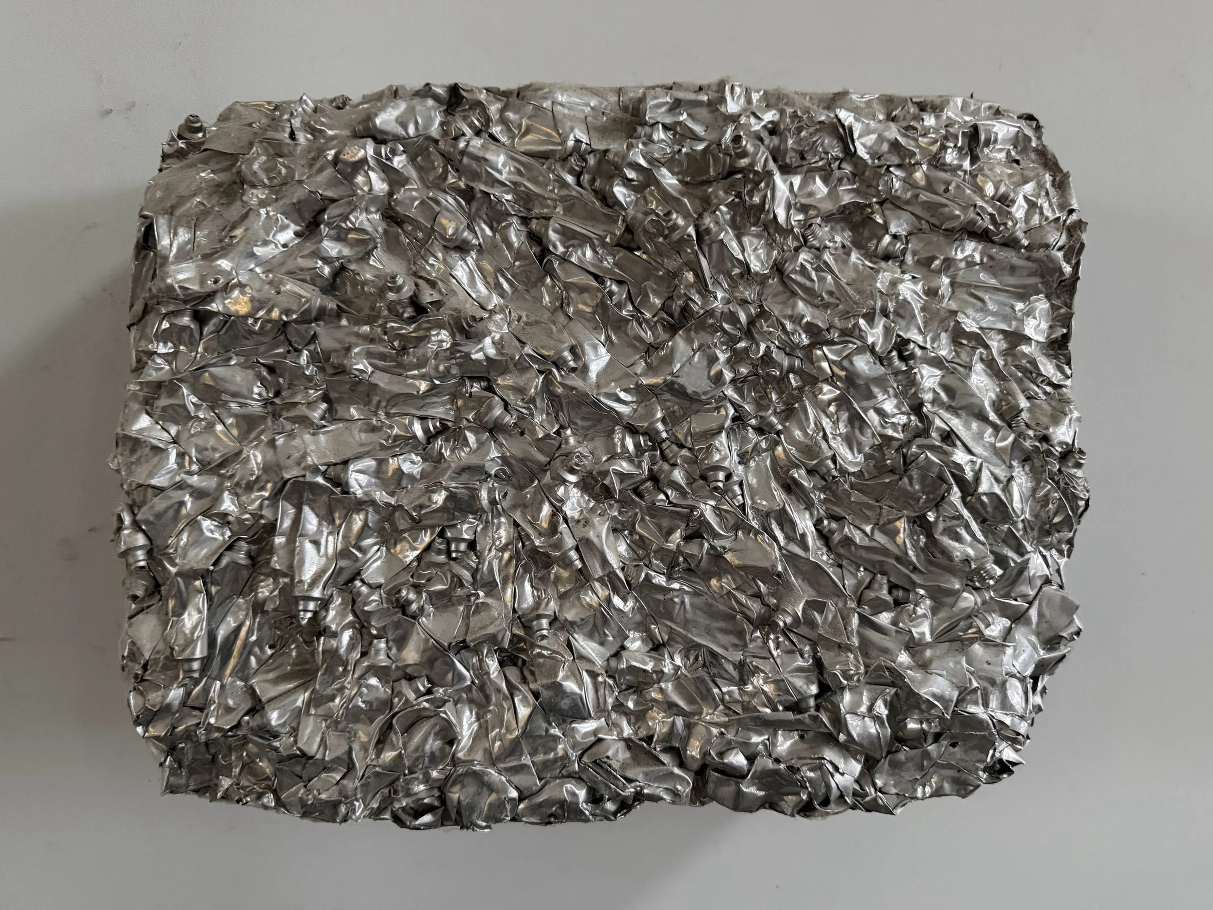A tightly compressed cube of crumpled aluminum foil.