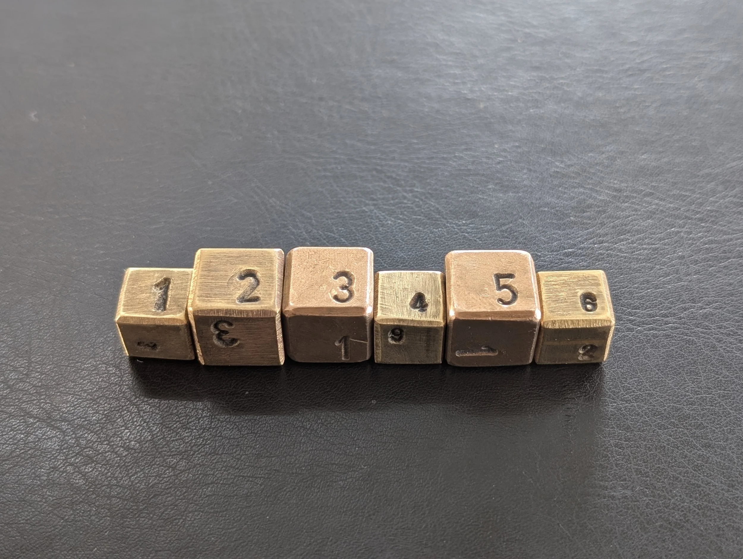 Six wooden blocks with numbers from 1 to 6 arranged in a line, some upside down, on a black surface.