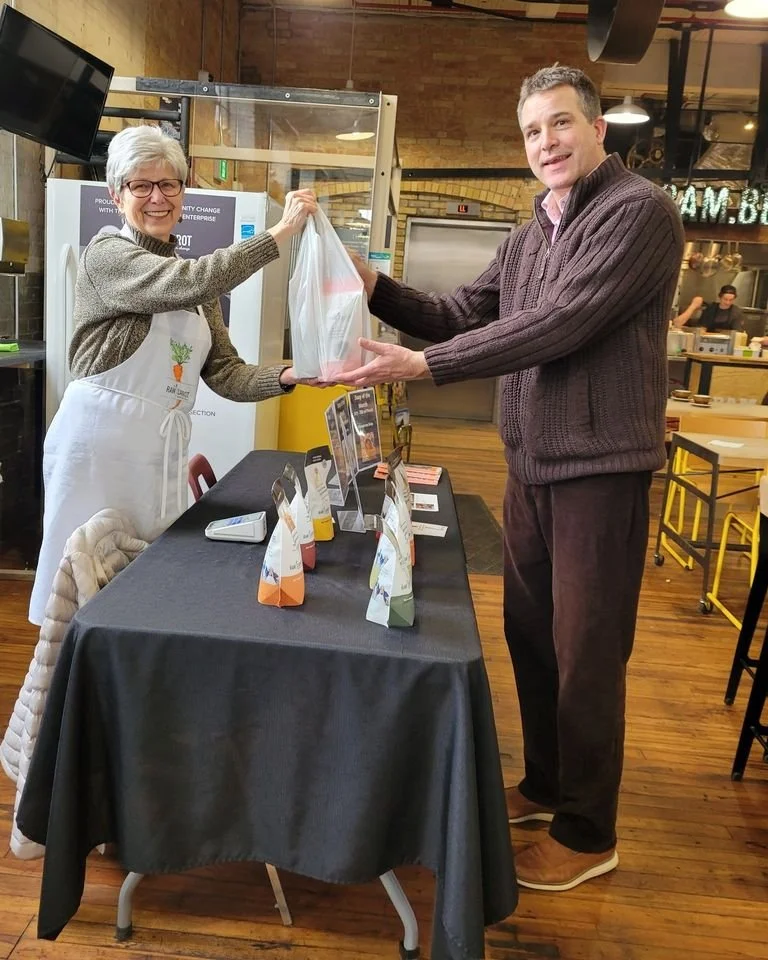 Volunteers at a market selling The Raw Carrot products.