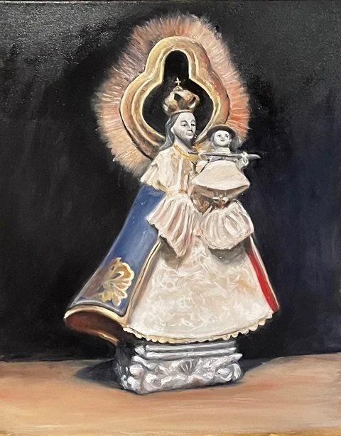 Religious sculpture of the Virgin Mary holding baby Jesus, with a halo and ornate decorations, set against a dark background.