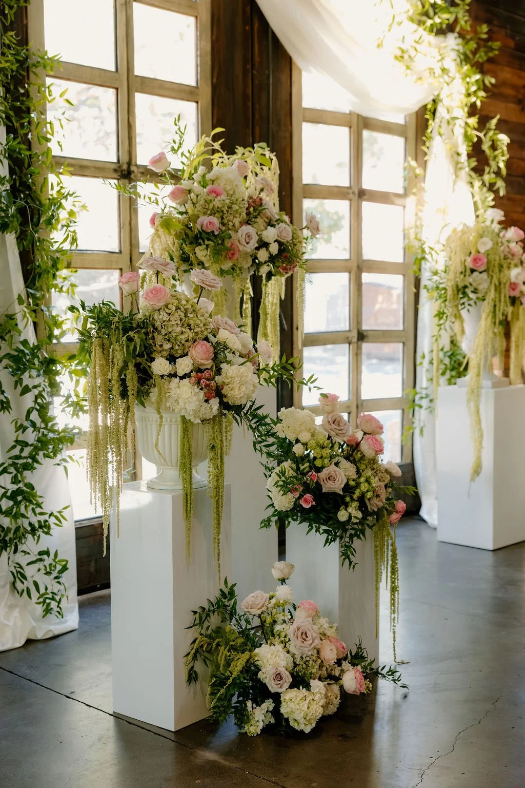 A breathtaking display of luxury wedding florals by Blooms by Tesla for a high-end celebration in Alpine, Utah. This design features a lush, romantic blend of creamy white roses, soft blush peonies, and delicate sweet peas, creating a timeless pink a